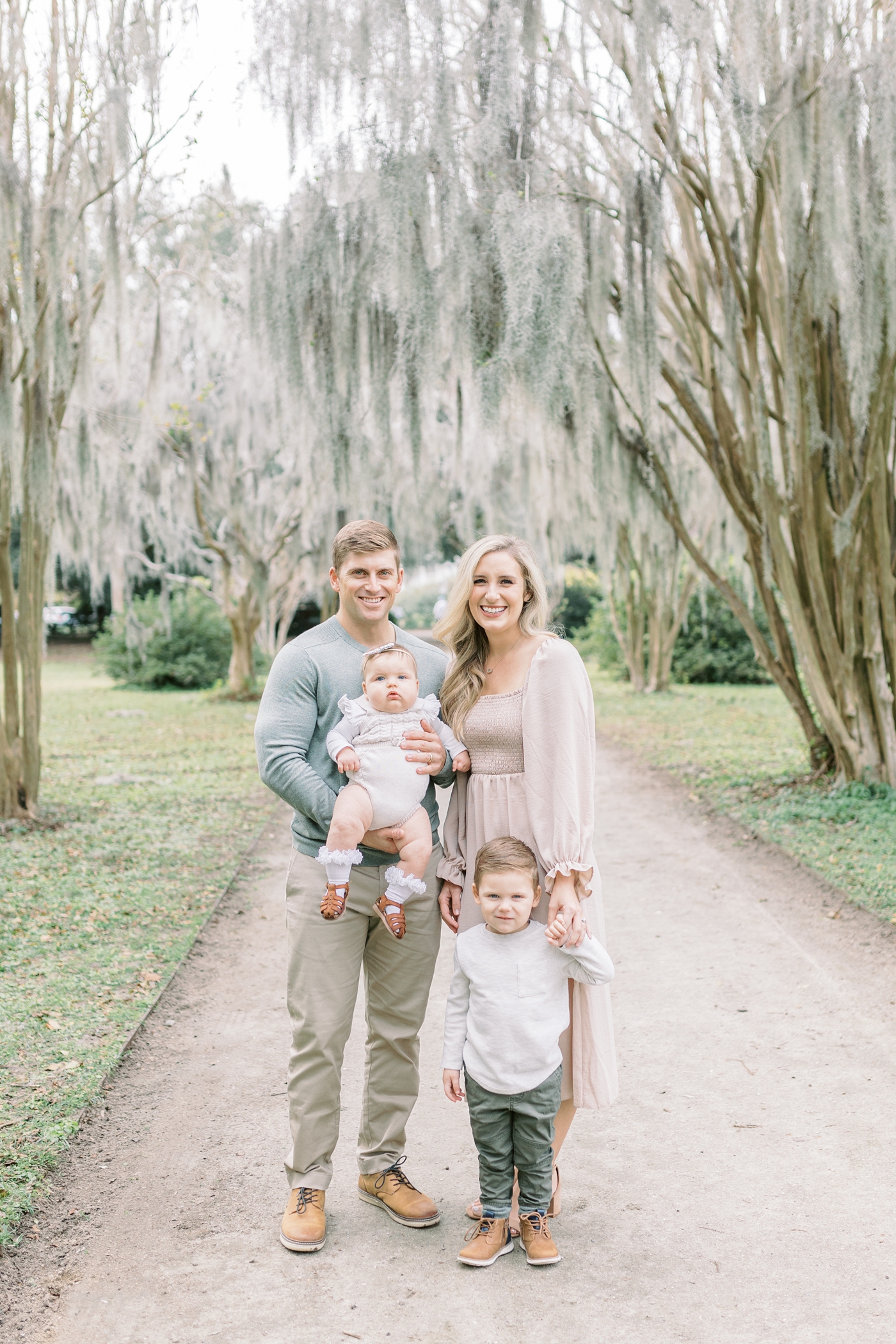 Family smiling at the camera during session at Hampton Park in Charleston SC.Photo by Caitlyn Motycka Photography.
