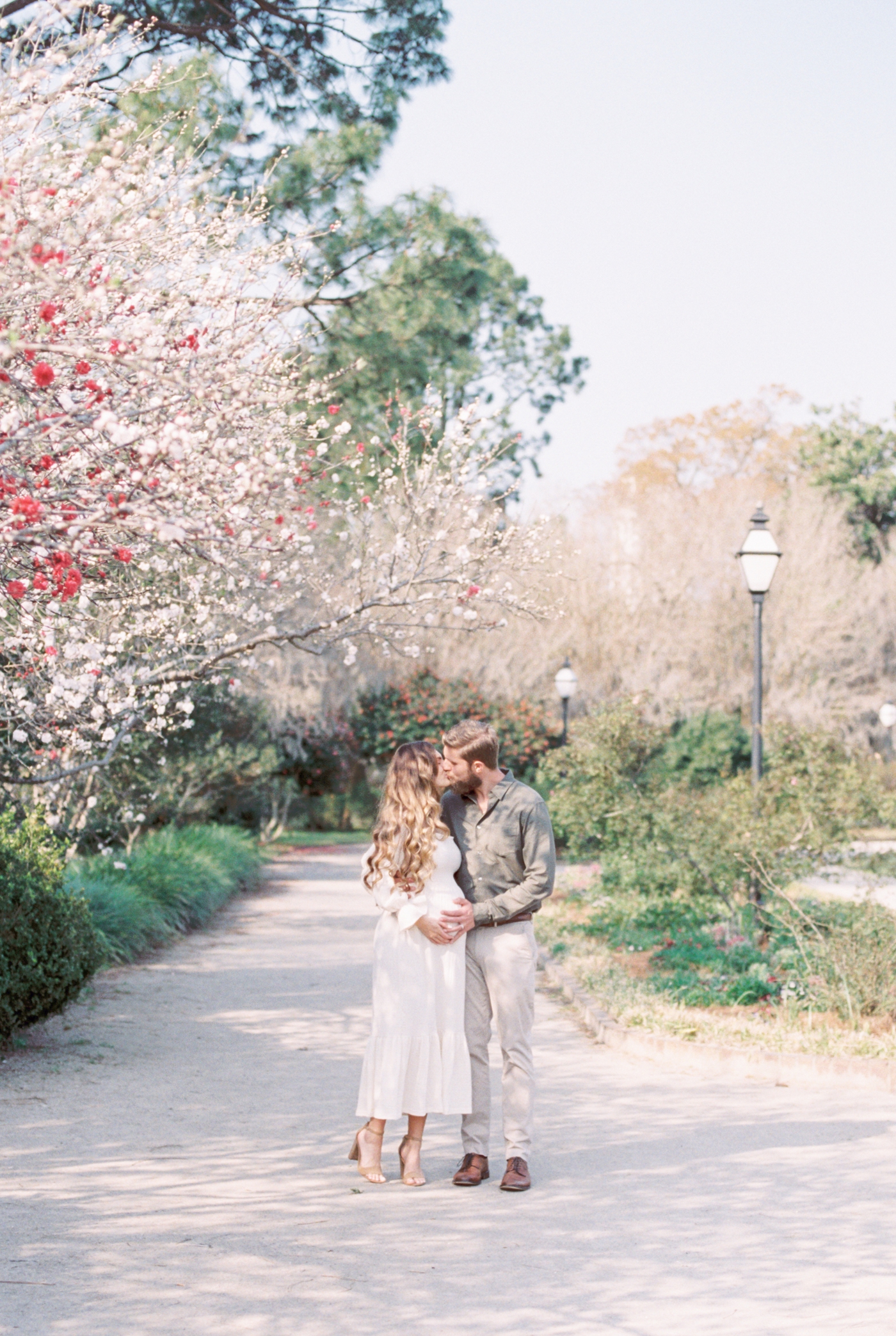 Couple kissing in Charleston SC park during a Spring maternity session. Photo by Caitlyn Motycka Photography.