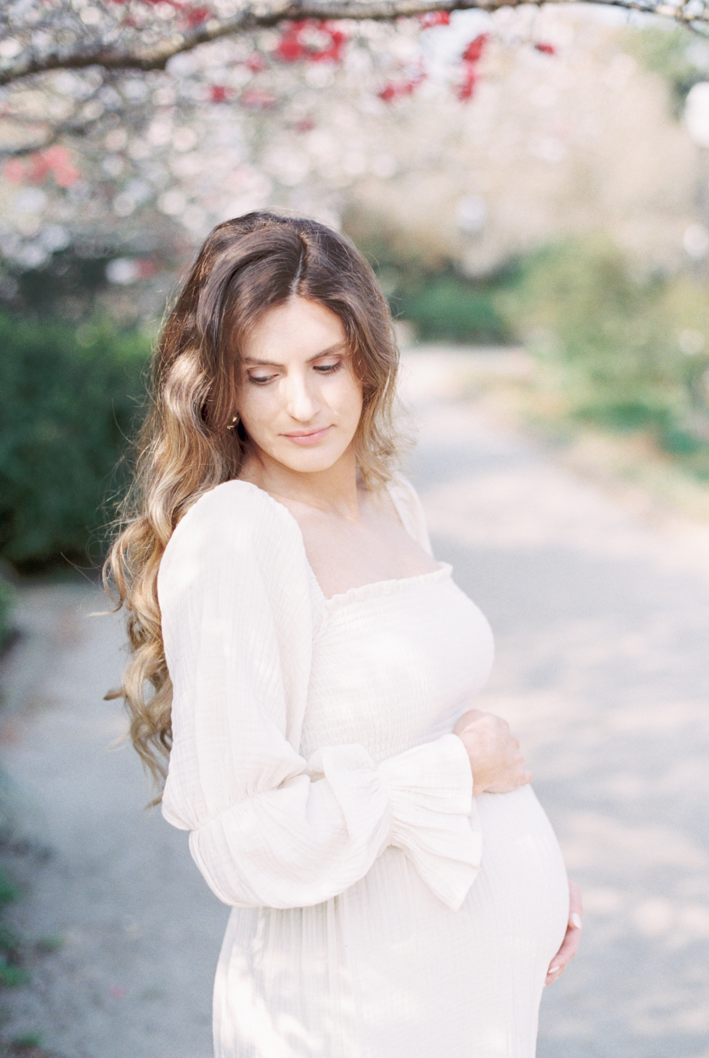 Expecting Mom in white dress during Spring maternity session in Charleston. Photo by fine art film photographer, Caitlyn Motycka Photography.