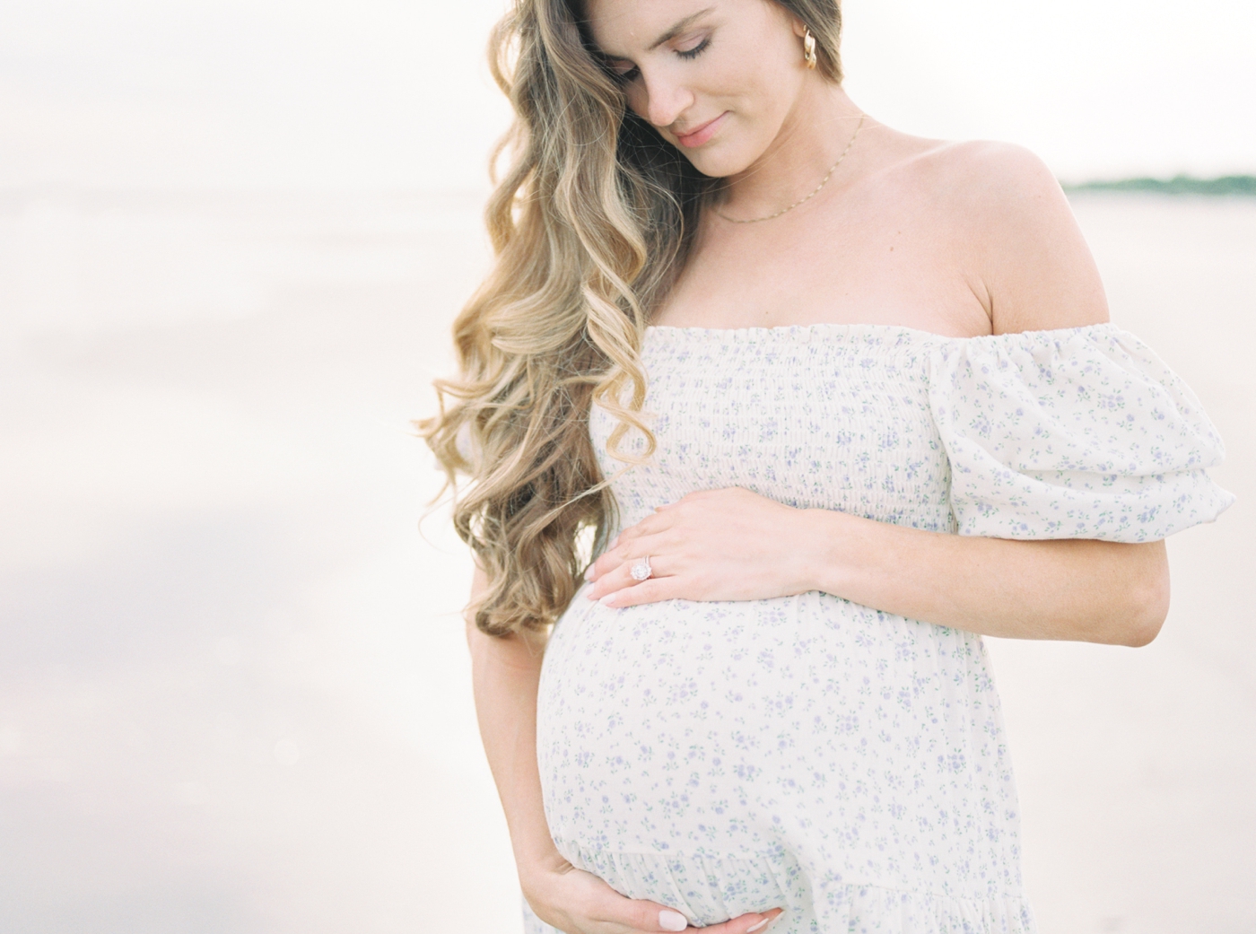 Mom to be in blue and white dress cradling her belly | Photo by Caitlyn Motycka Photography.