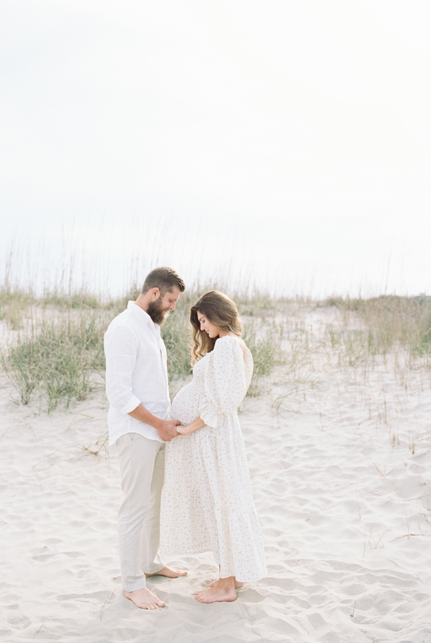 Mom and dad holding hands during maternity Session on the beach | Photo by Caitlyn Motycka Photography.