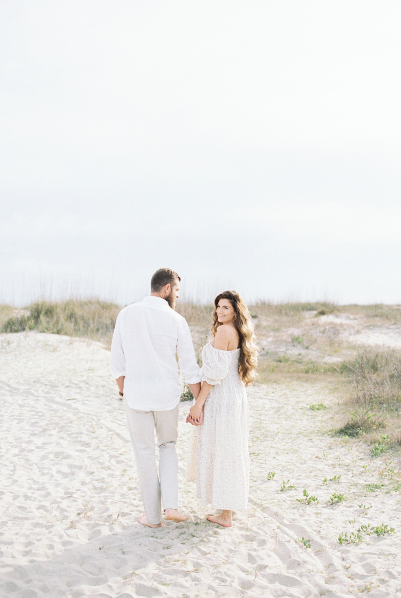 Couple walking on the beach at Sullivans Island | Photo by Caitlyn Motycka Photography.