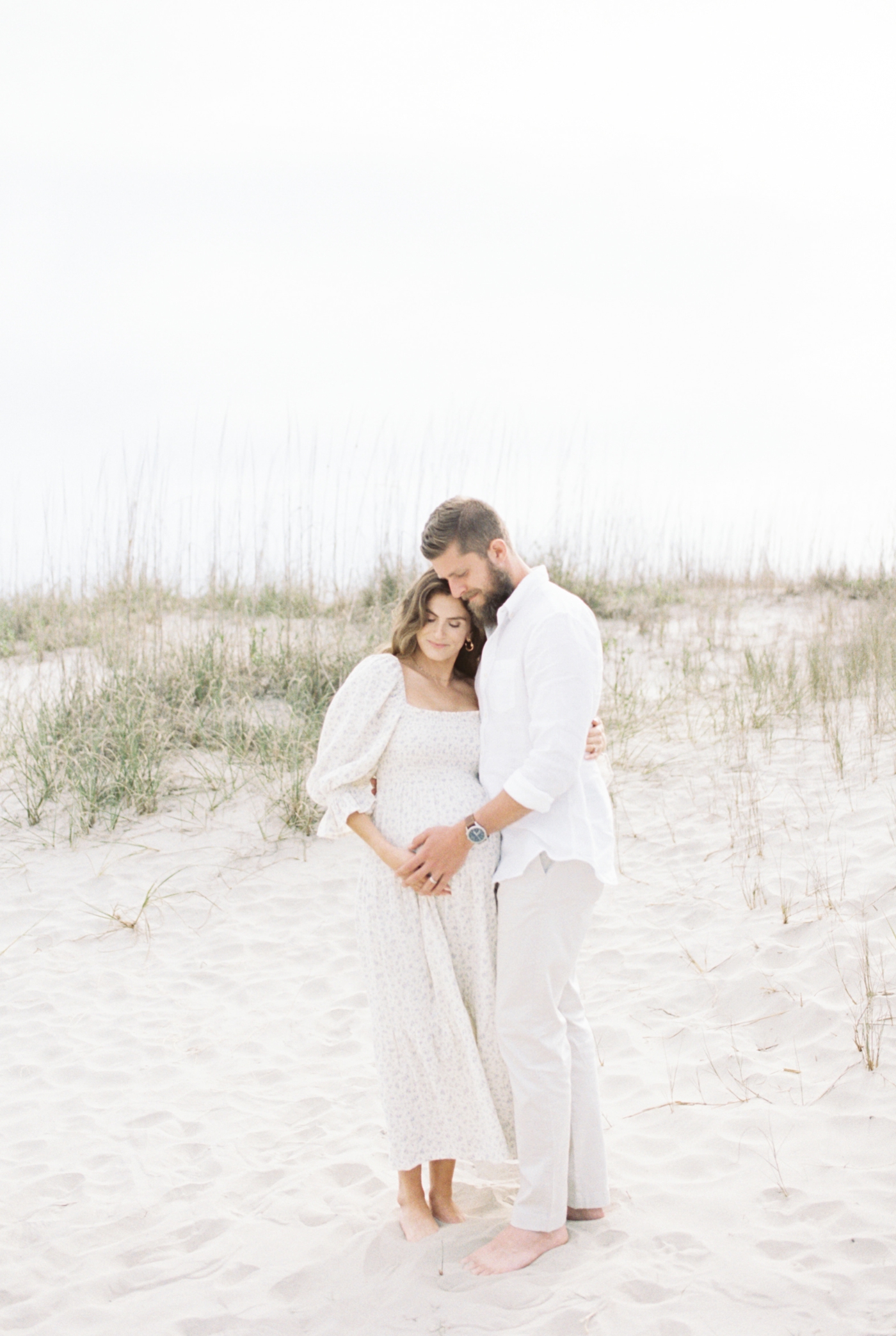 Mother and father to be cradling moms belly at Sullivans Island | Photo by Caitlyn Motycka Photography.