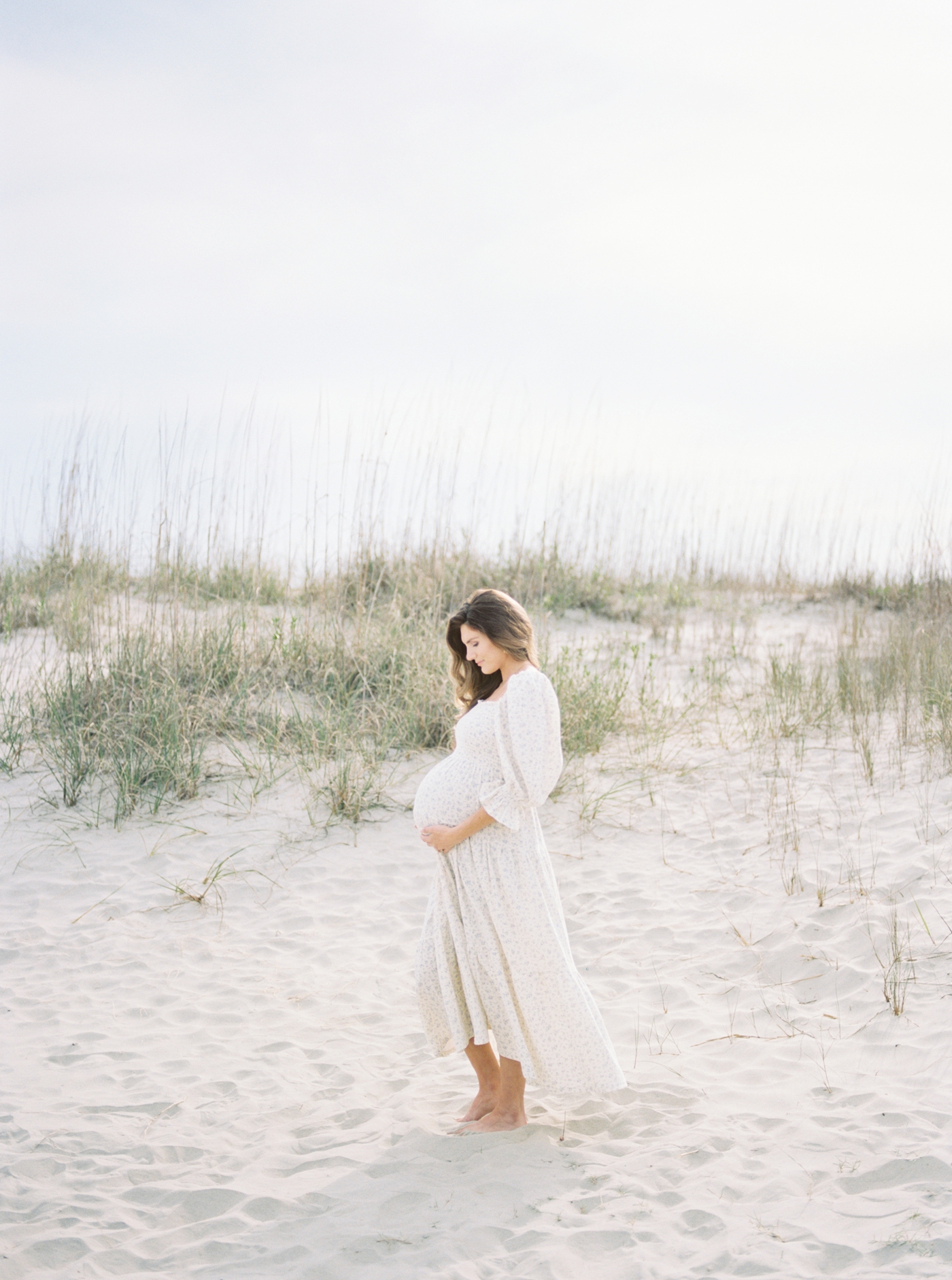 Mother to be on Sullivans Island cradling belly | Photo by Caitlyn Motycka Photography.