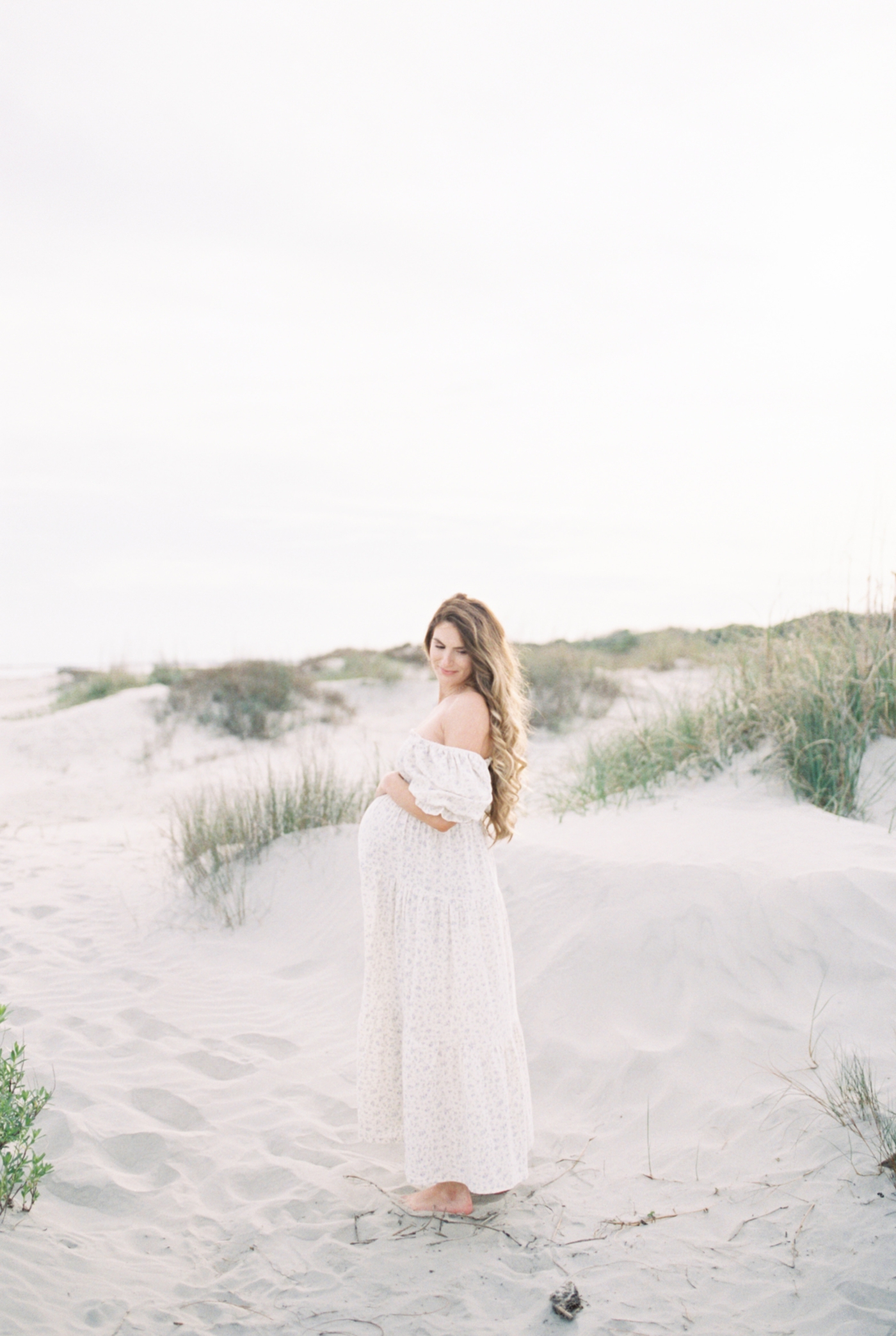 Mother to be in long white dress on Sullivans Island | Photo by Caitlyn Motycka Photography.