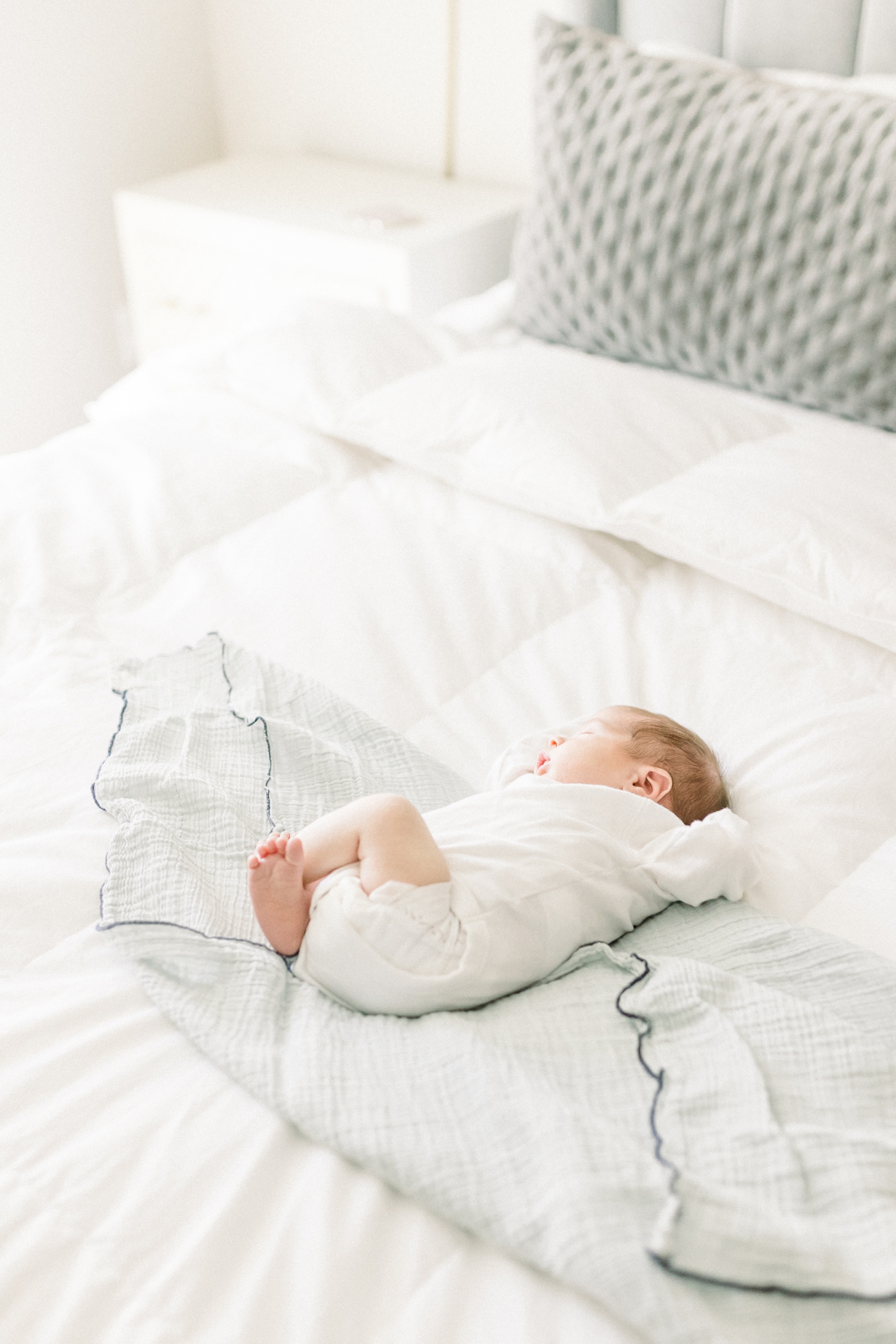 Newborn baby sleeping on a bed | Photo by Caitlyn Motycka Photography.