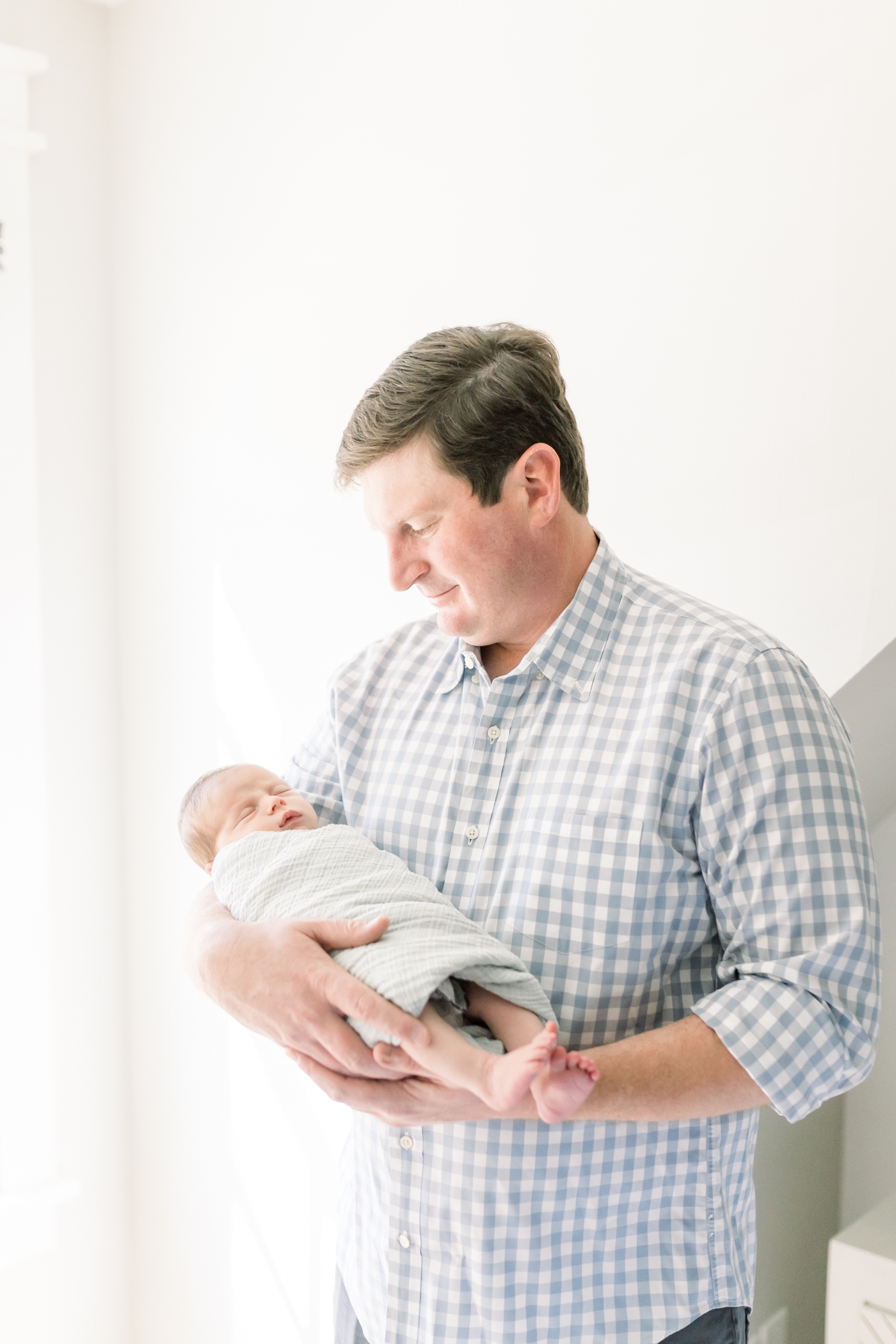 Dad holding his new baby during their in home newborn session | Photo by Caitlyn Motycka Photography.