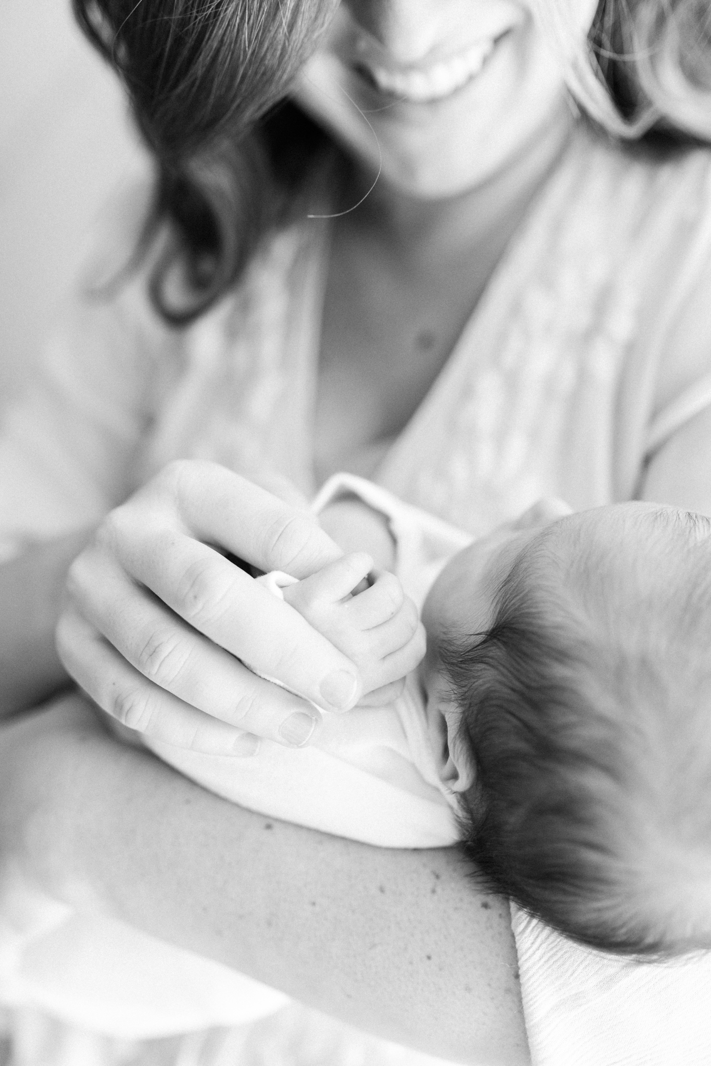 Black and white photo of mom holding newborn baby's hand | Photo by Caitlyn Motycka Photography.