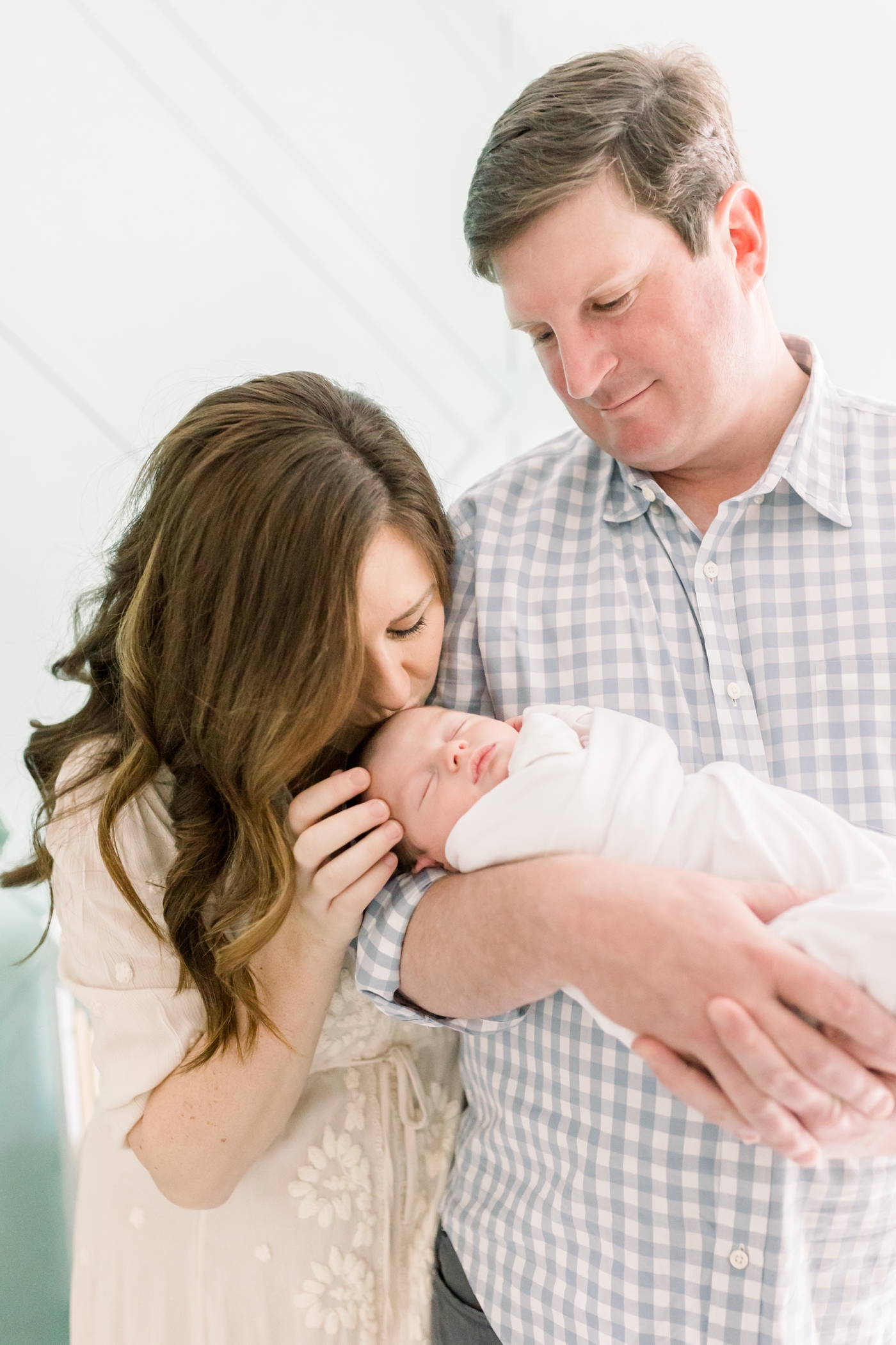Mom kissing newborn baby held by dad | Photo by Caitlyn Motycka Photography.