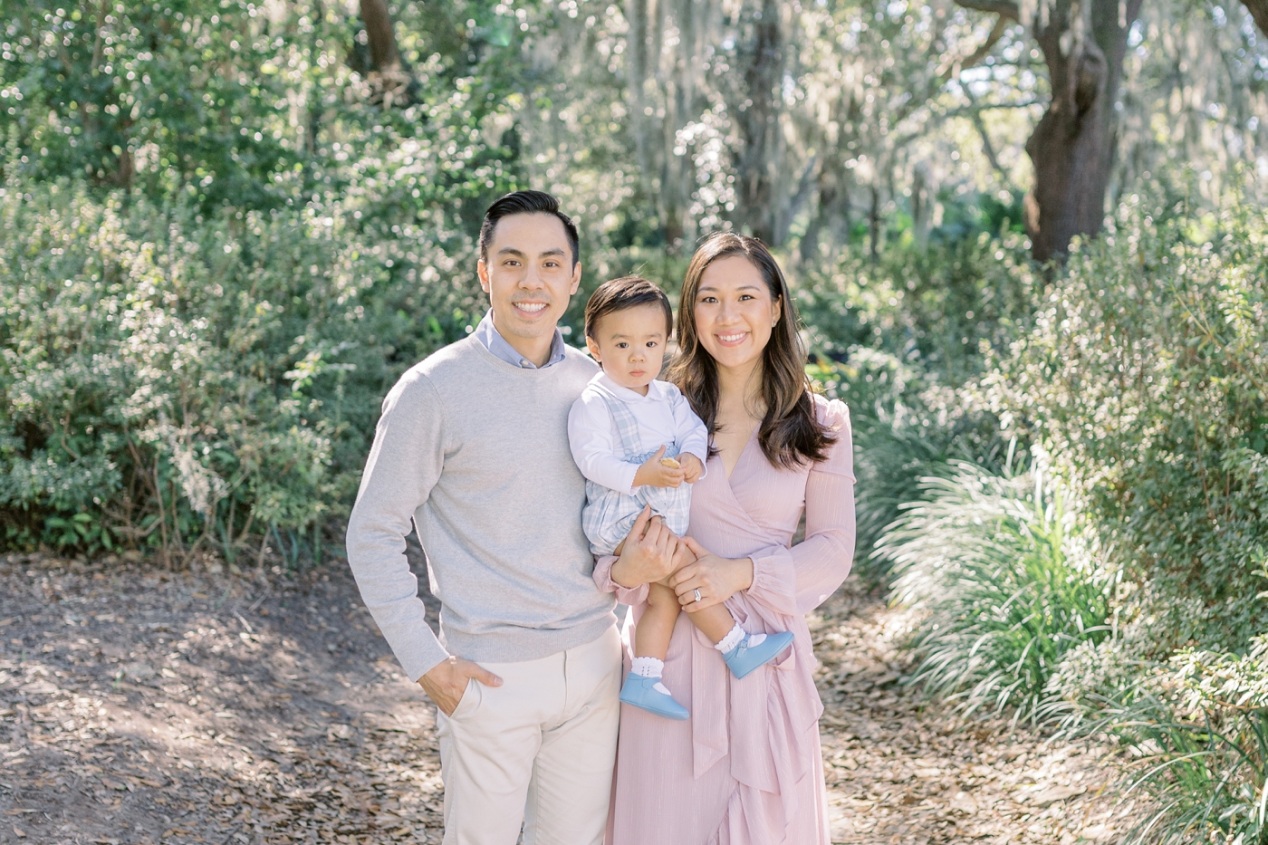 Dad mom and toddler boy smiling for the camera in the park | Photo by Caitlyn Motycka Photography