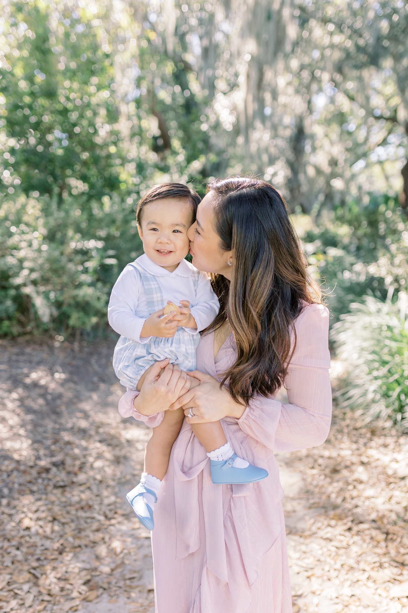 Mom kissing baby boy in blue on the cheek | Photo by Caitlyn Motycka Photography