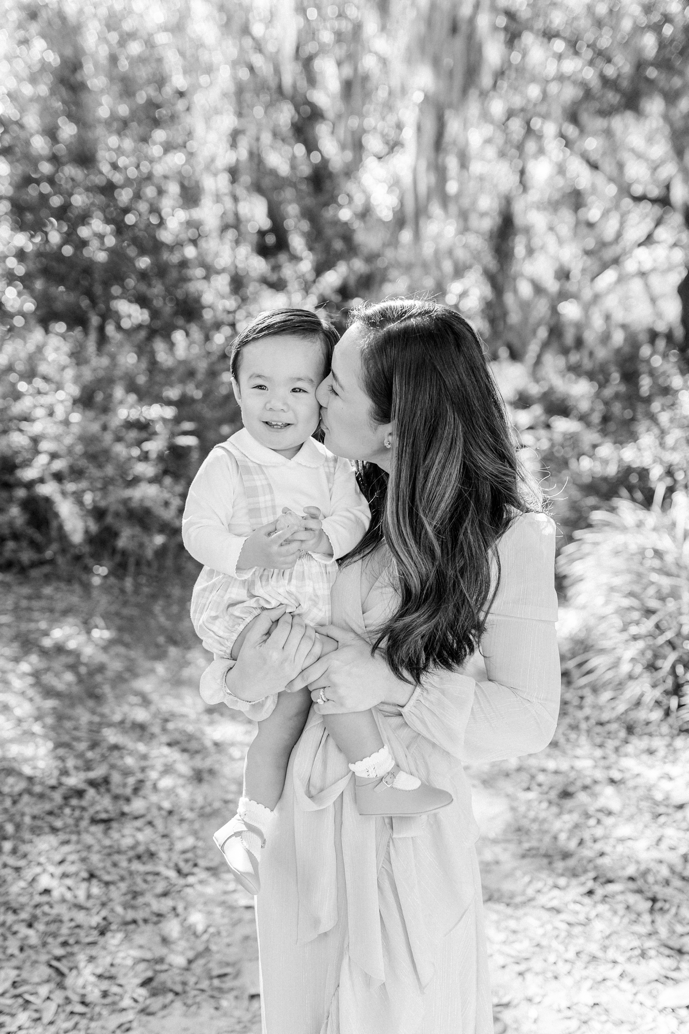 Black and white photo of mom kissing toddler boy on the cheek | Photo by Caitlyn Motycka Photography