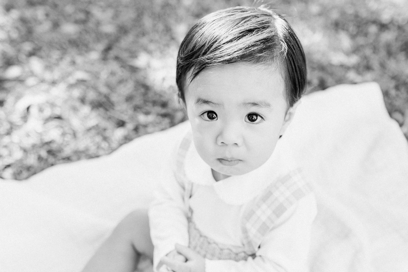 Black and white photo of baby boy sitting on blanket in the park | Photo by Caitlyn Motycka Photography