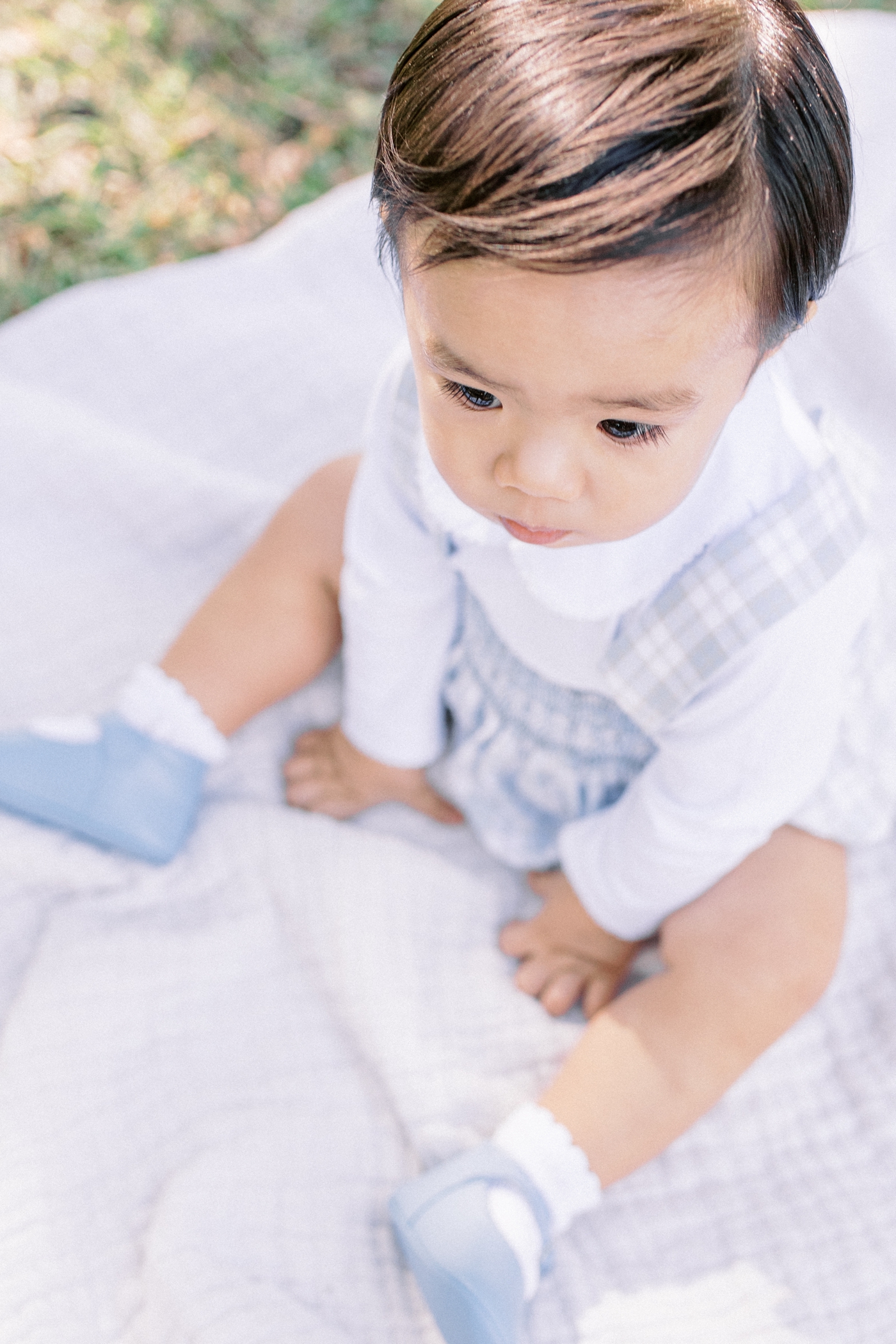 Baby boy in blue eyelash details sitting in the park | Photo by Caitlyn Motycka Photography