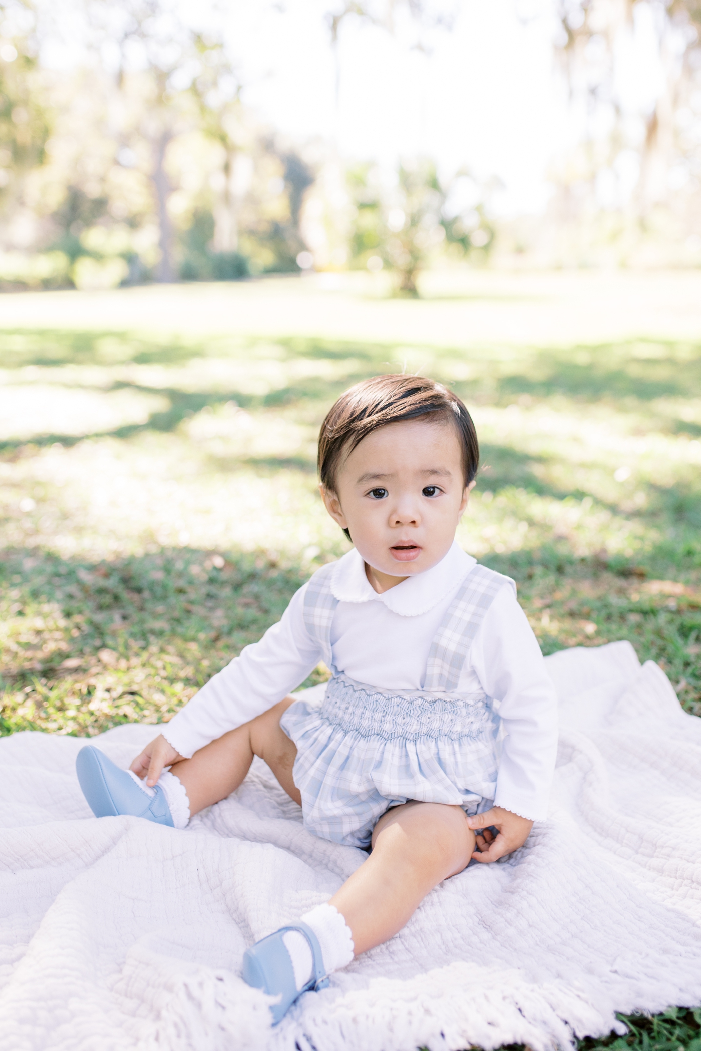 Toddle boy in blue sits on a blanket in Hampton Park for mini session | Photo by Caitlyn Motycka Photography
