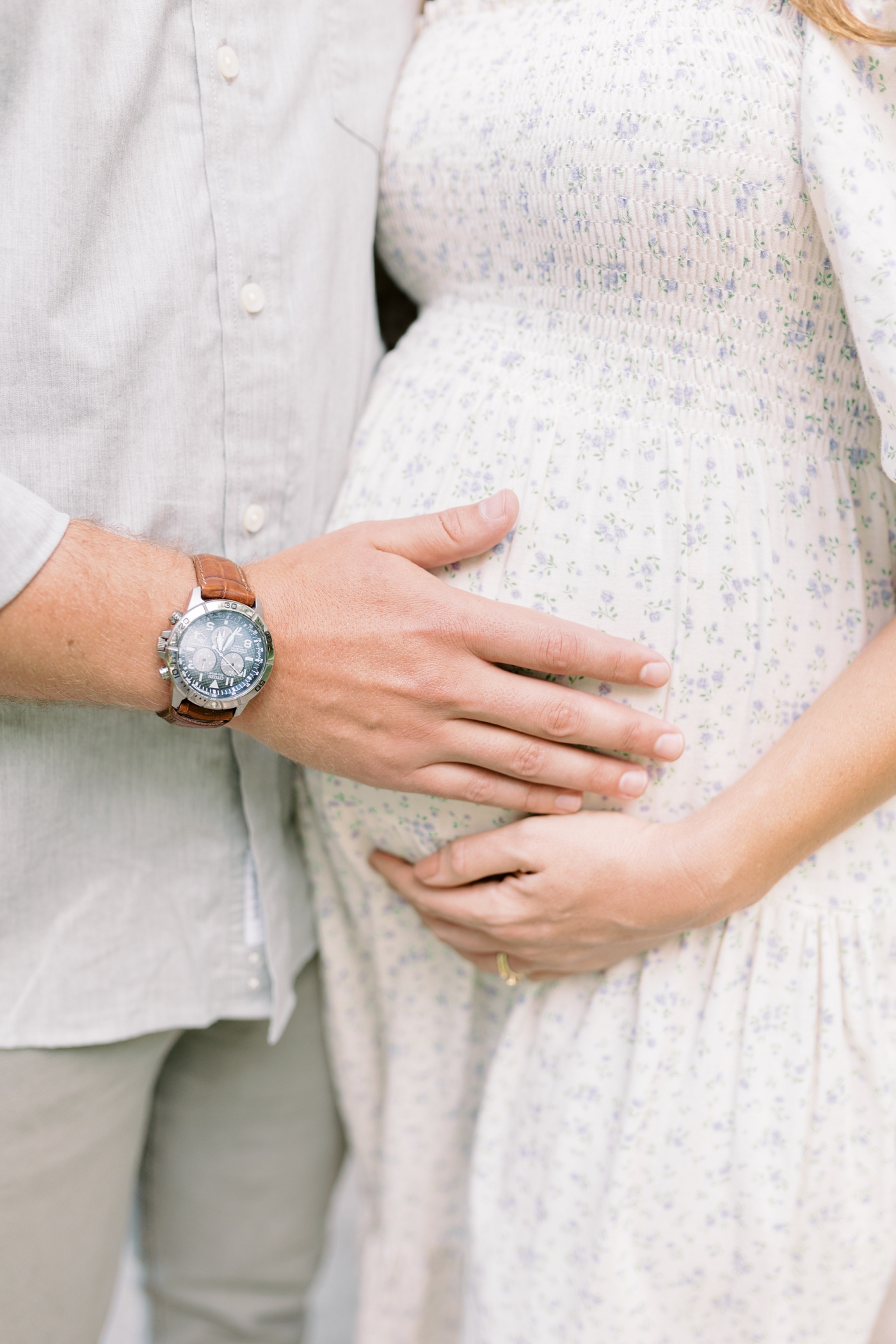 Detail of dad's hand cradling mom's belly | Photo by Caitlyn Motycka Photography.