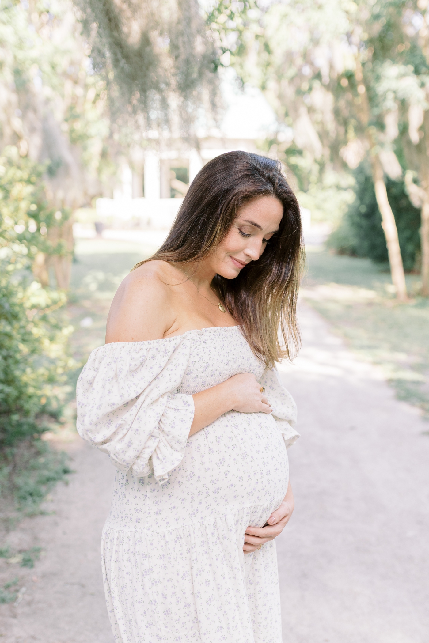 Mom to be holding her belly in the park | Photo by Caitlyn Motycka Photography.