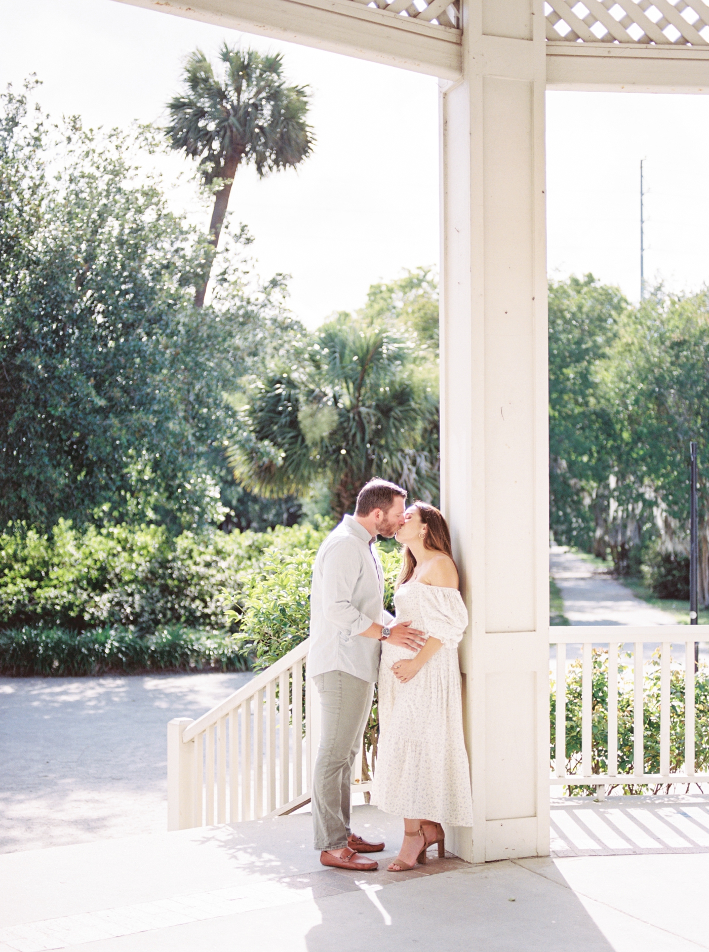 Mom and dad to be kissing under a gazebo | Photo by Caitlyn Motycka Photography.