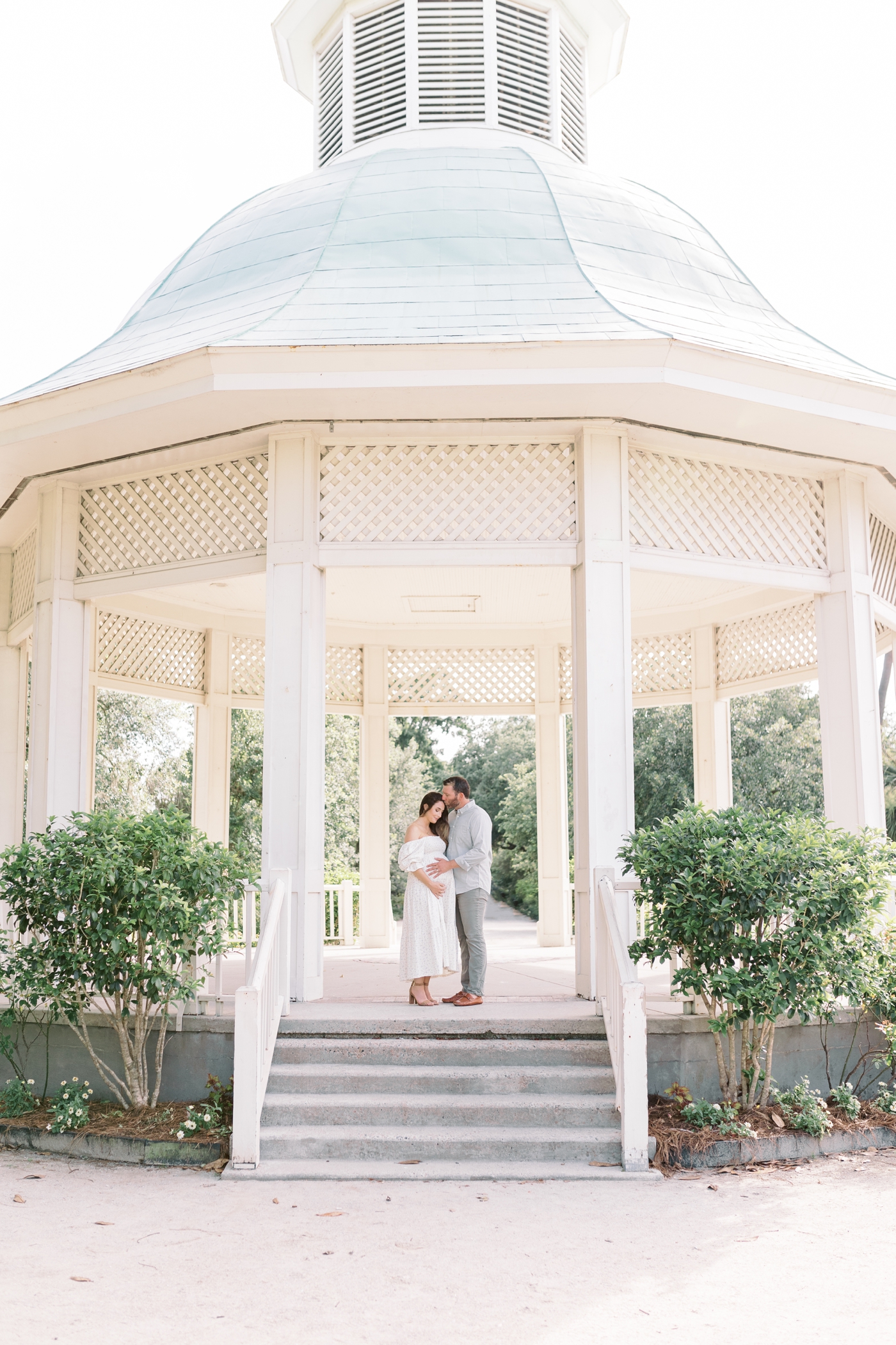 Mom and dad to be standing under a gazebo in Hampton Park | Photo by Caitlyn Motycka Photography.
