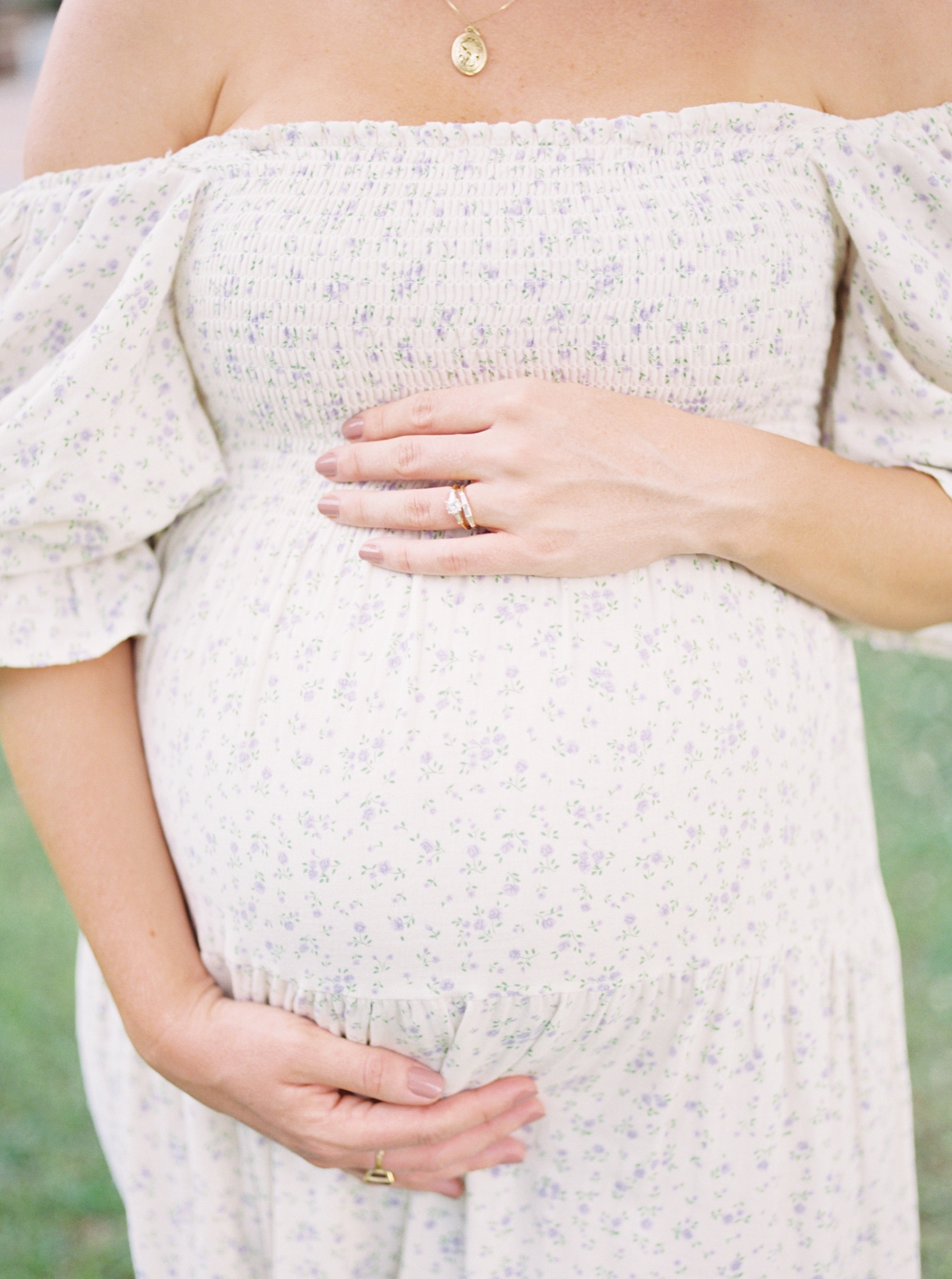Expectant mom holding her belly wearing a floral print dress | Photo by Caitlyn Motycka Photography.