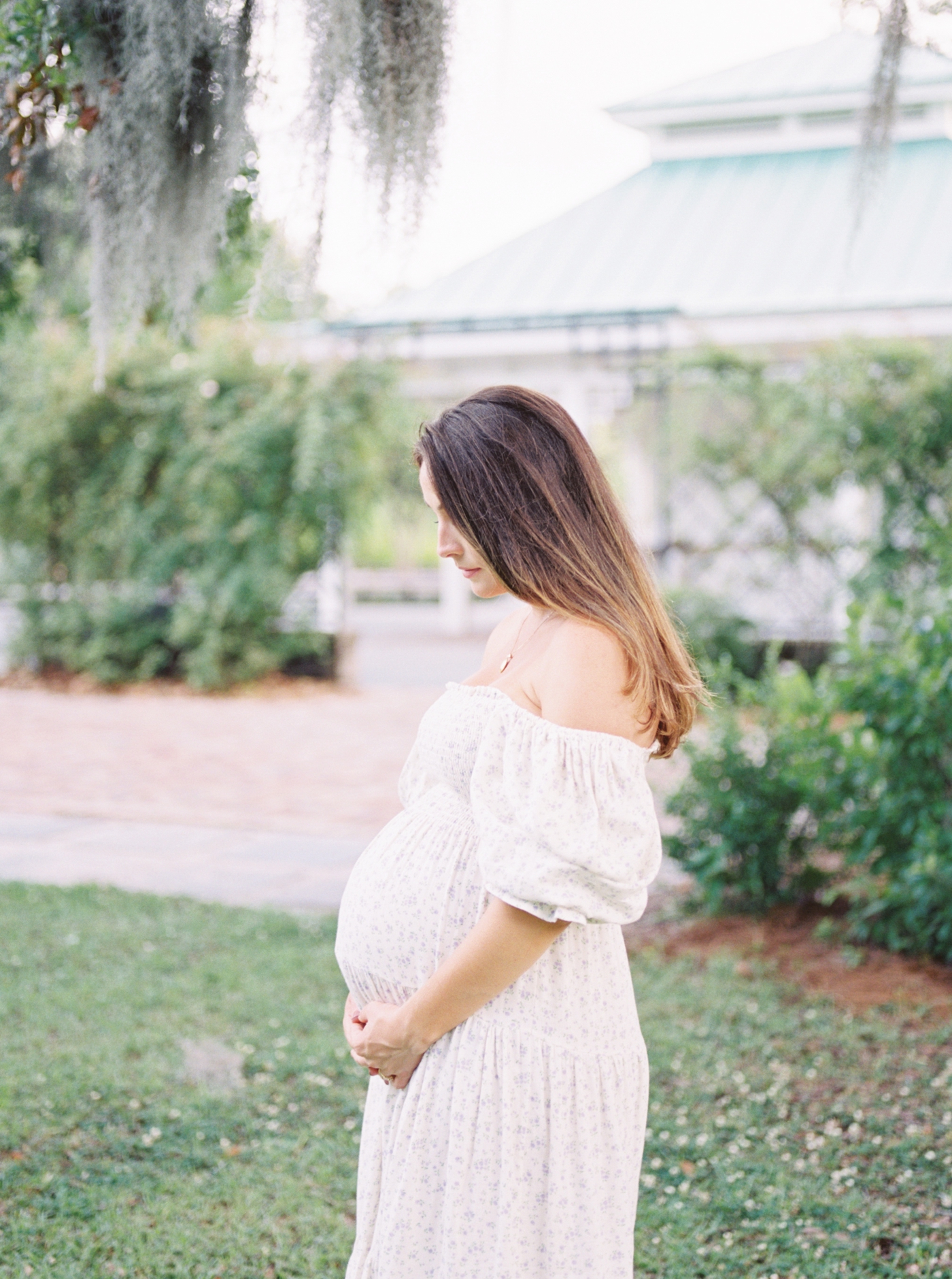 Mom to be in floral dress cradling her belly | Photo by Caitlyn Motycka Photography.