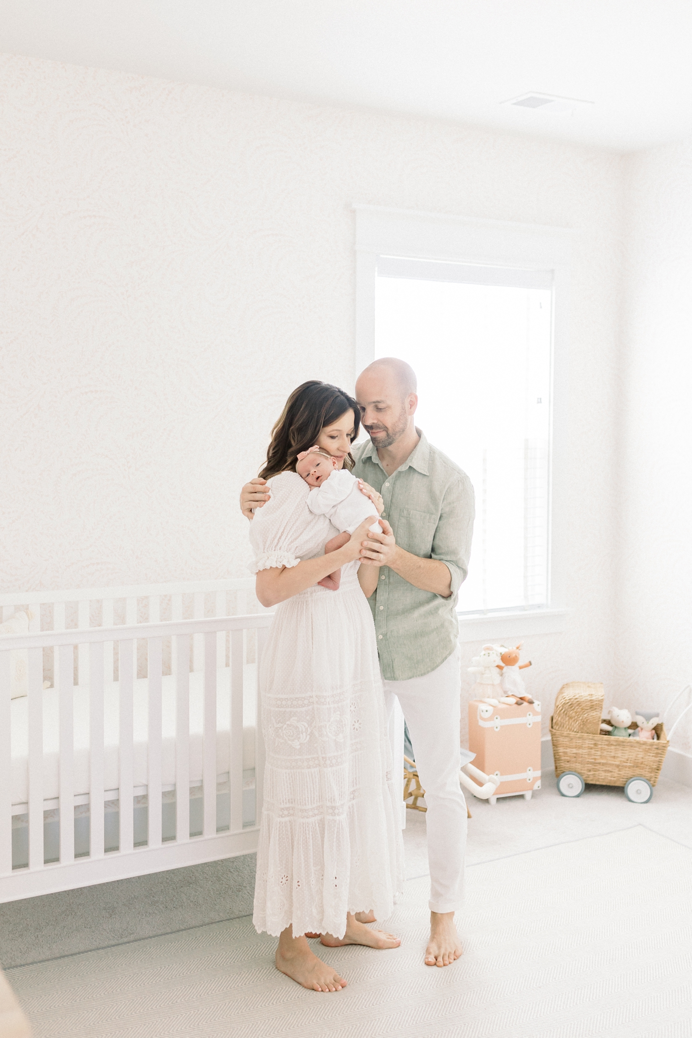 Mom and dad holding their new baby in her nursery during their lifestyle newborn session | Photo by Caitlyn Motycka Photography