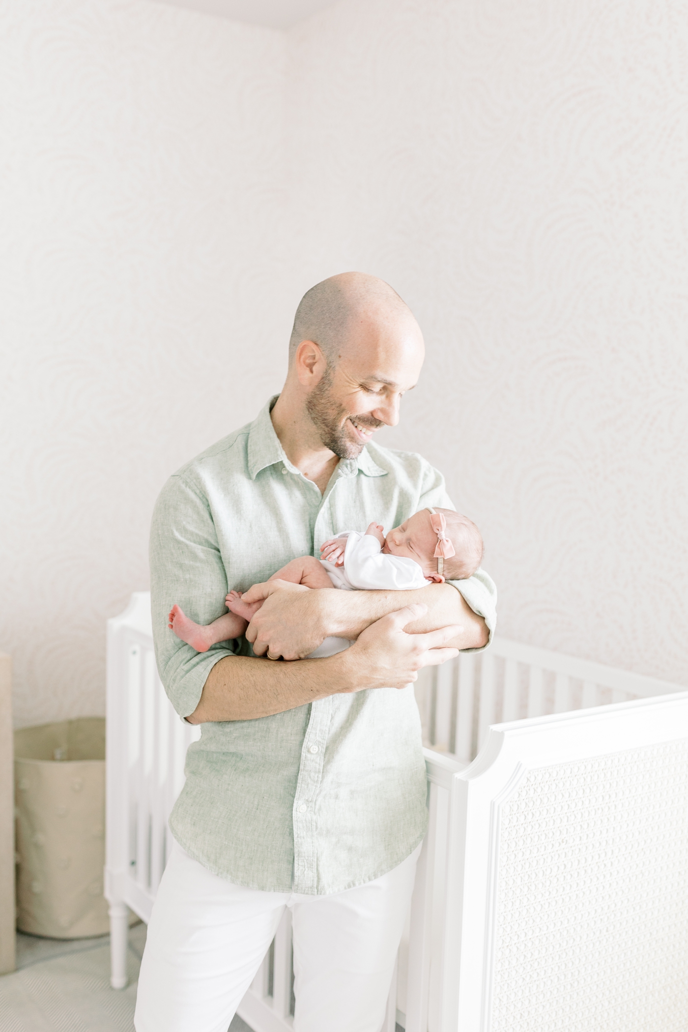 Dad in green shirt smiling down at newborn baby girl during their lifestyle newborn session | Photo by Caitlyn Motycka Photography