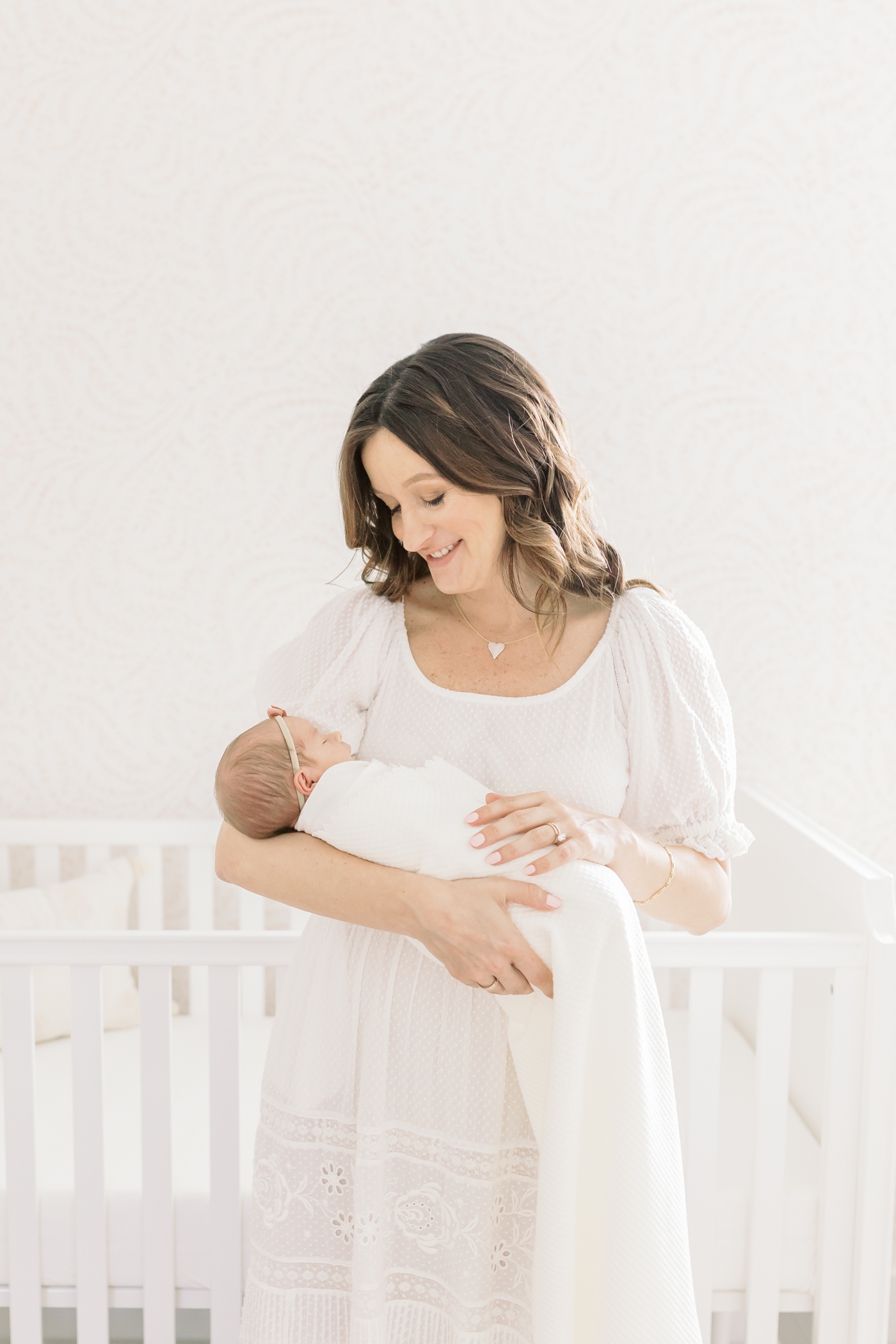 Mom in eyelet dress holding new baby during their lifestyle newborn session | Photo by Caitlyn Motycka Photography