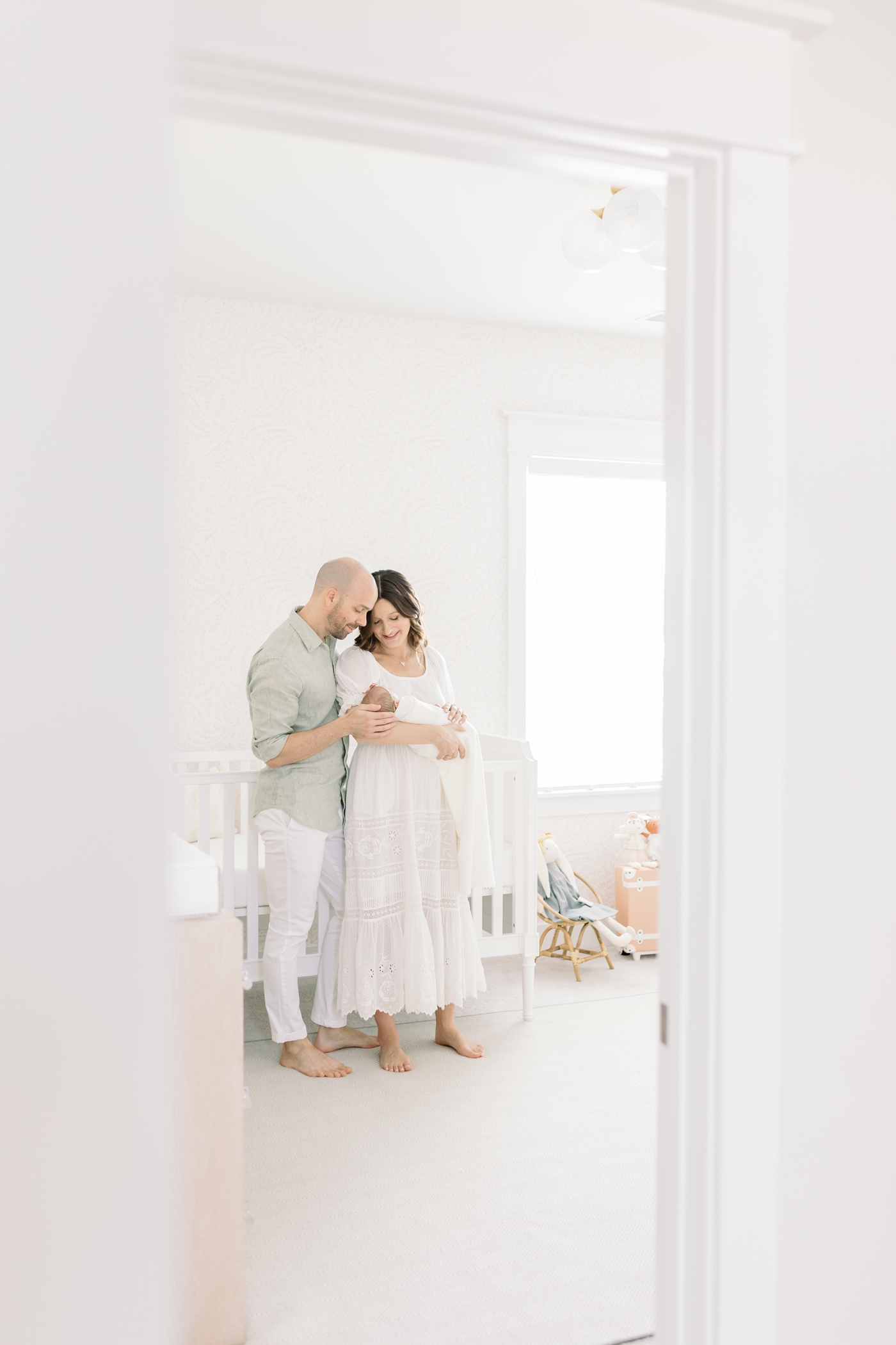 Mom and dad holding their new baby in the nursery during their lifestyle newborn session | Photo by Caitlyn Motycka Photography