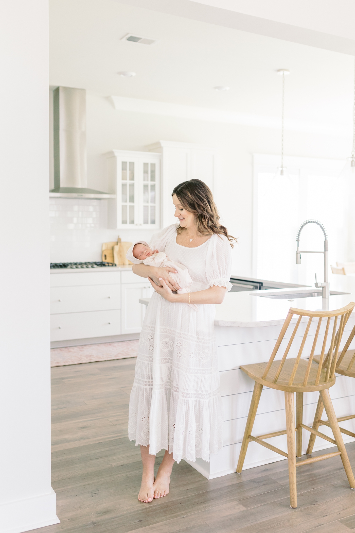 Mom holding her baby in the kitchen during their Lifestyle Newborn Session | Photo by Caitlyn Motycka Photography.