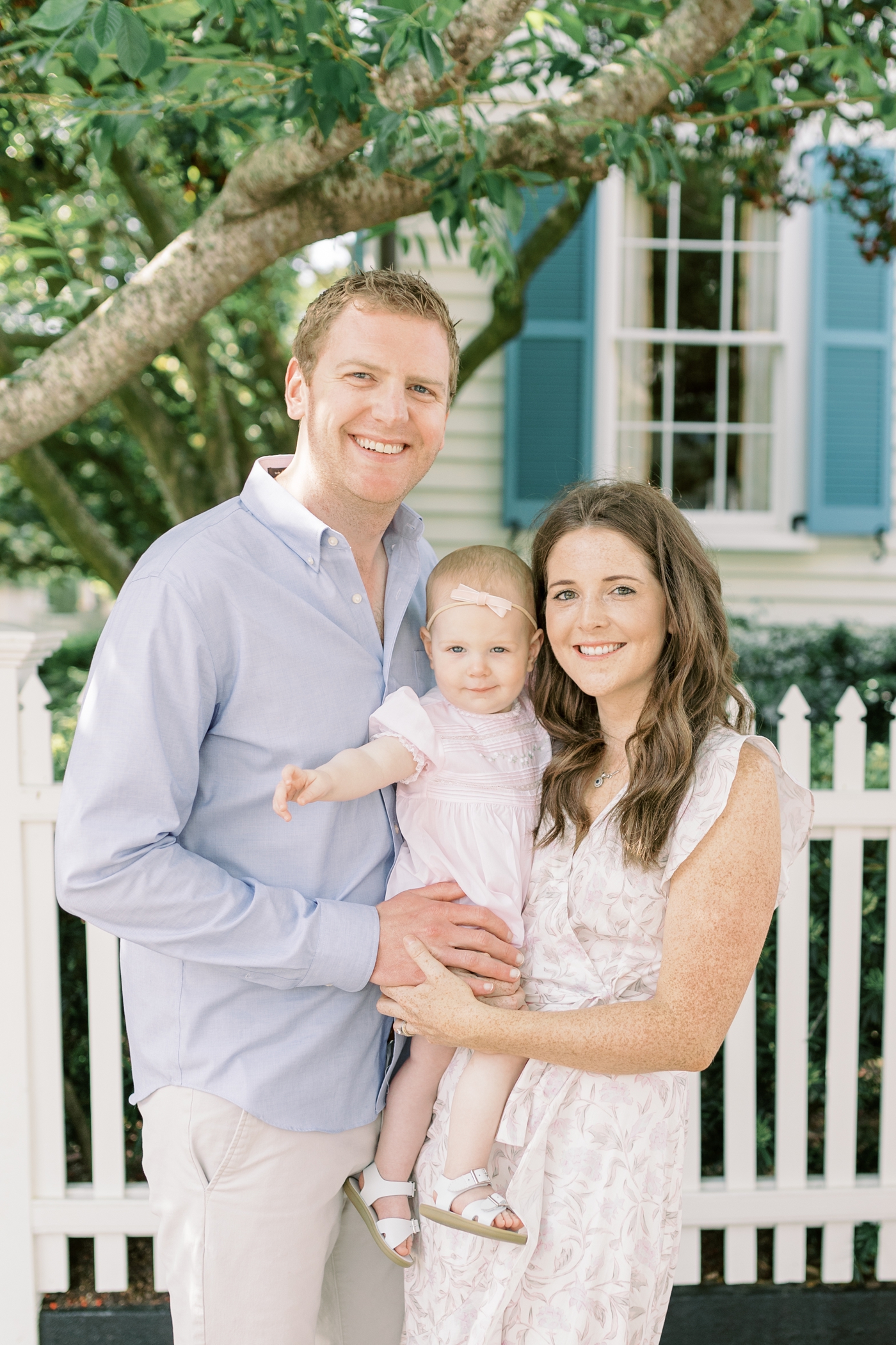 Mom dad and daughter smiling in downtown Charleston for 18 Month session | Photo by Caitlyn Motycka Photography.