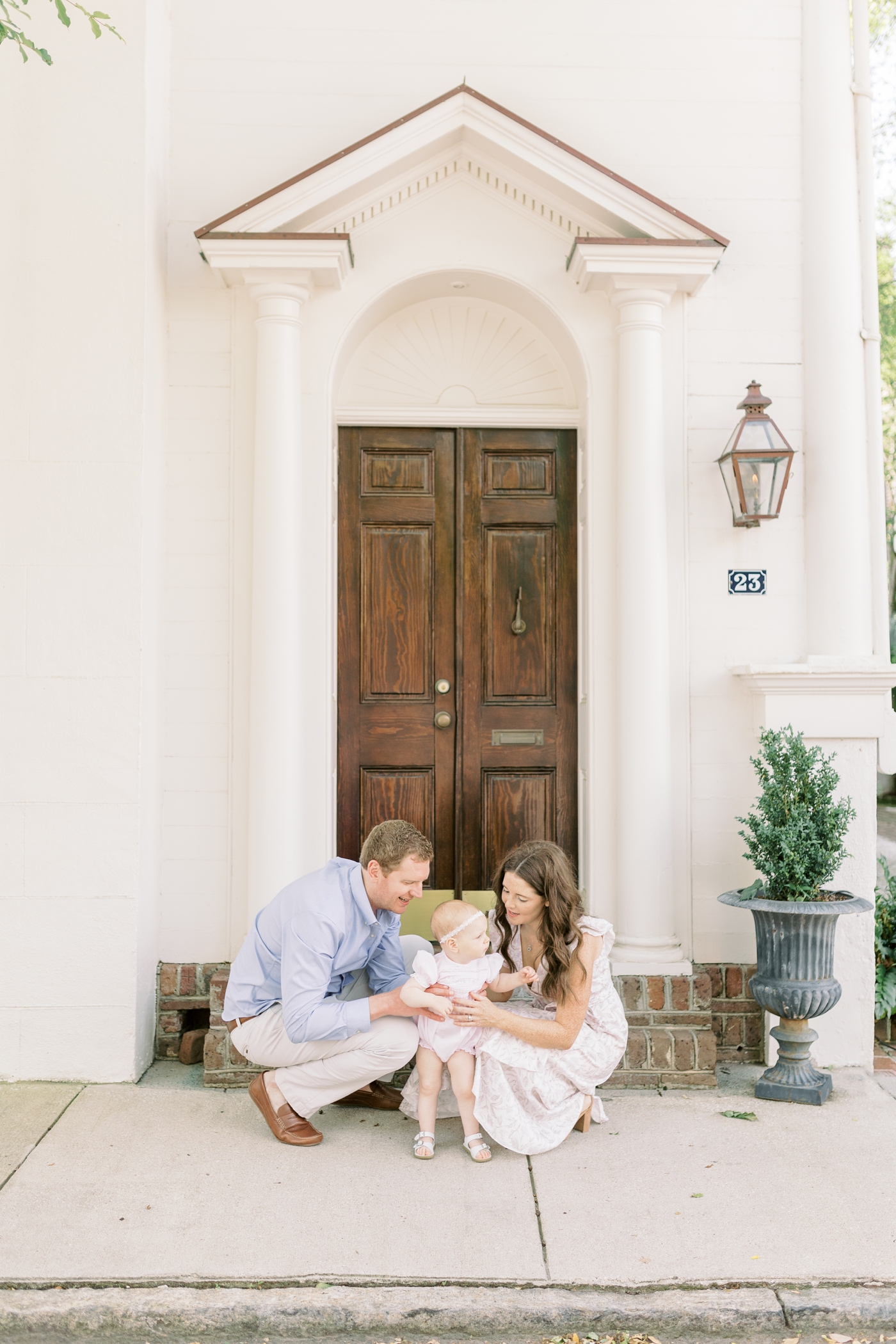 Mom dad and baby girl sit on steps downtown Charleston during 18 month session | Photo by Caitlyn Motycka Photography.