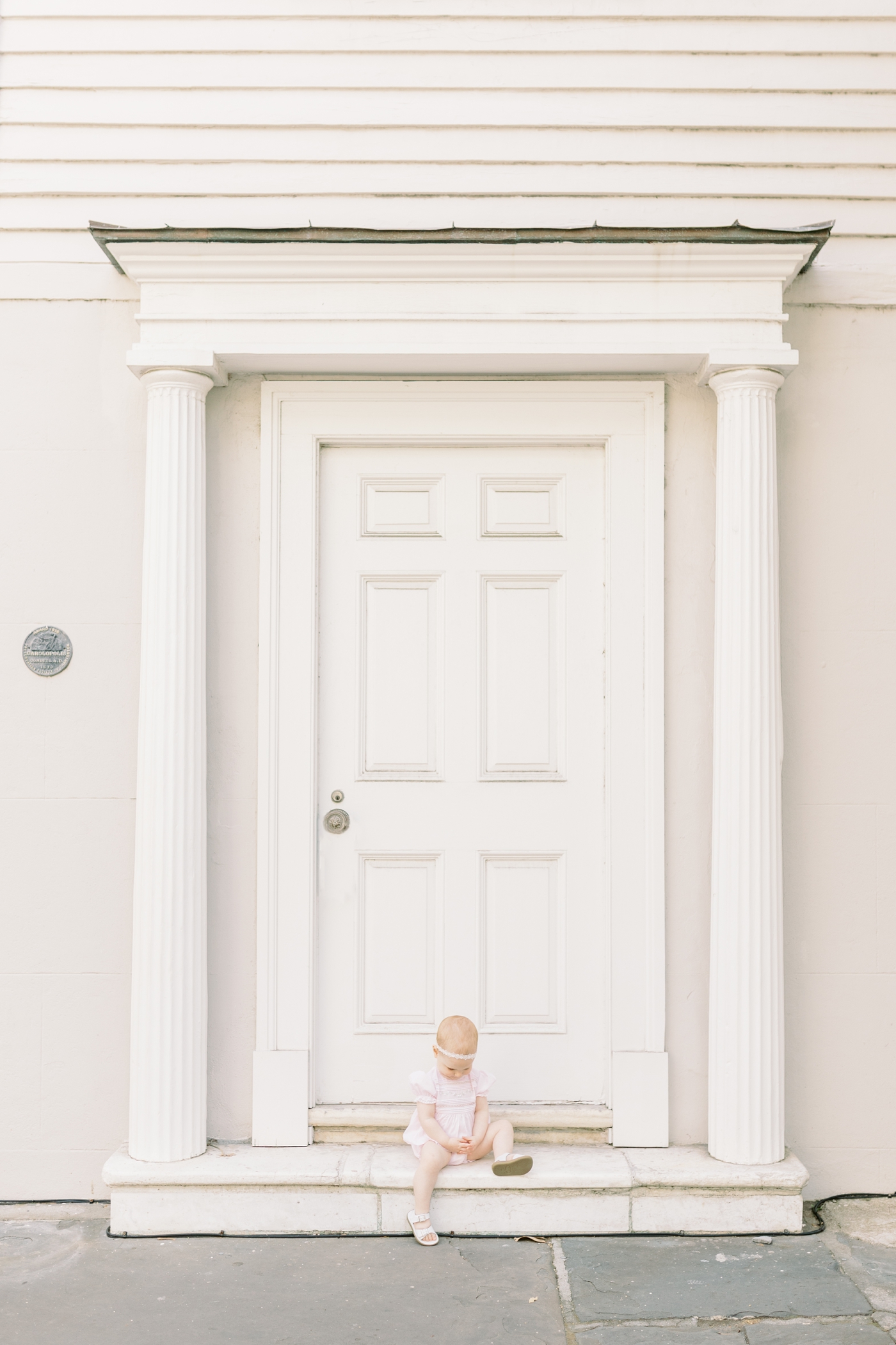 Baby girl in pink sits on the front stoop in downtown Charleston | Photo by Caitlyn Motycka Photography.