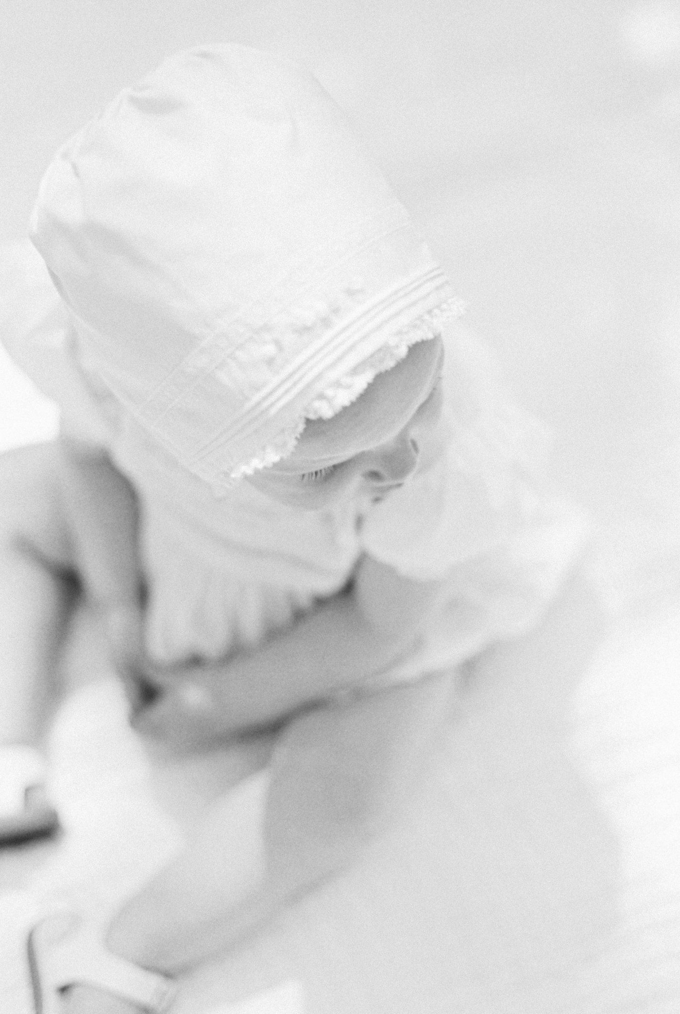 Black and white film image of baby girl in a bonnet | Photo by Caitlyn Motycka Photography.