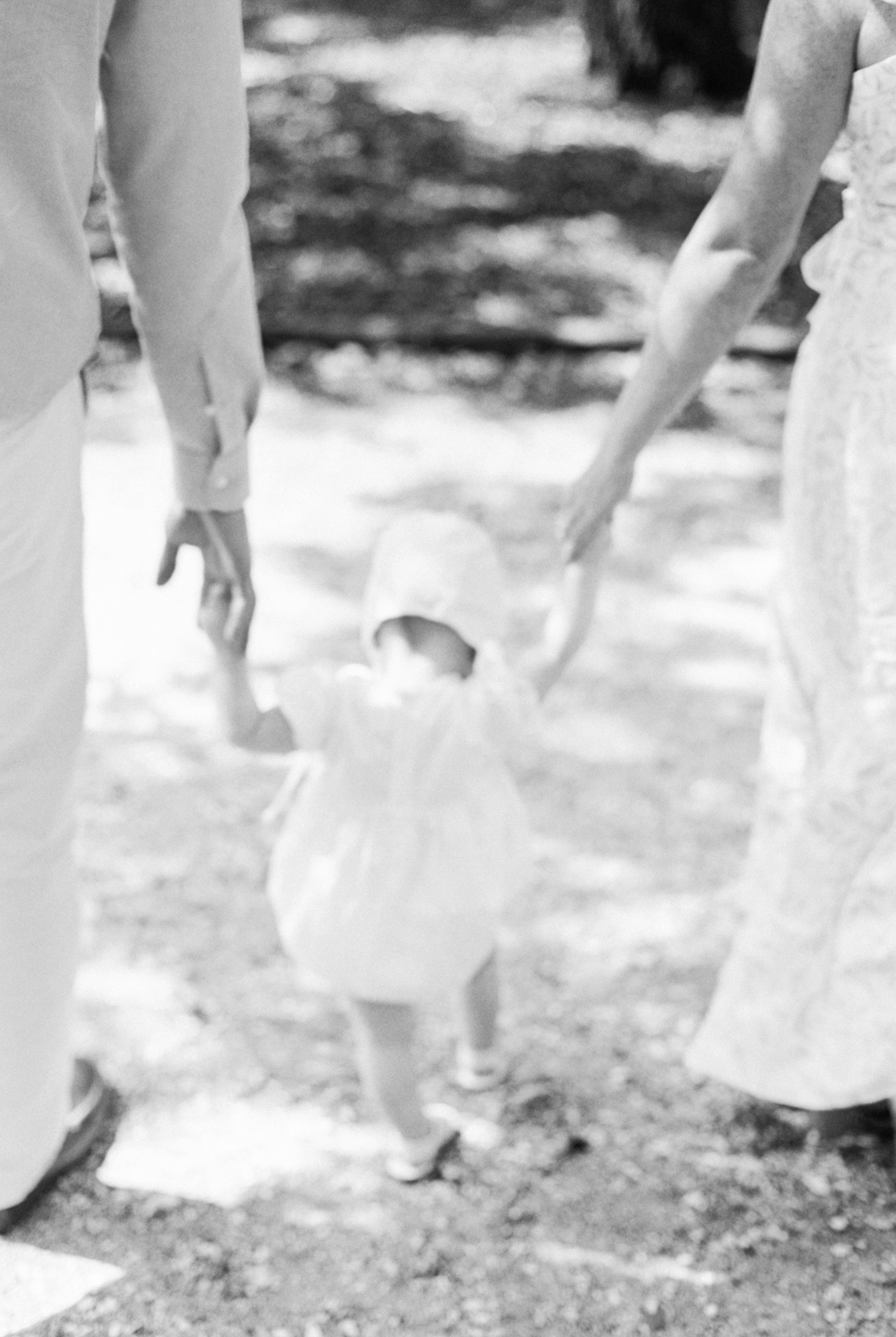 Detail of mom and dad helping baby girl walk during 18 month session downtown charleston | Photo by Caitlyn Motycka Photography.