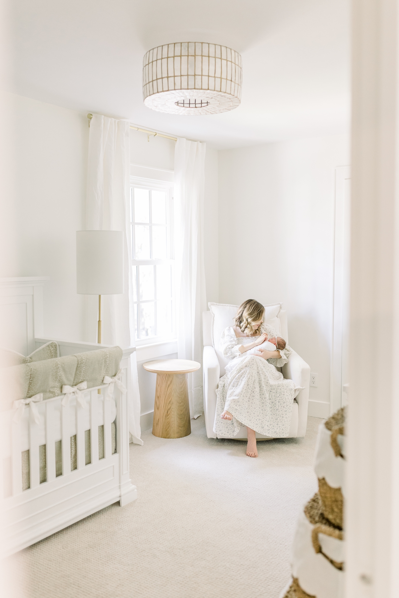 Mom holding new baby in a neutral nursery | Photo by Caitlyn Motycka Photography.