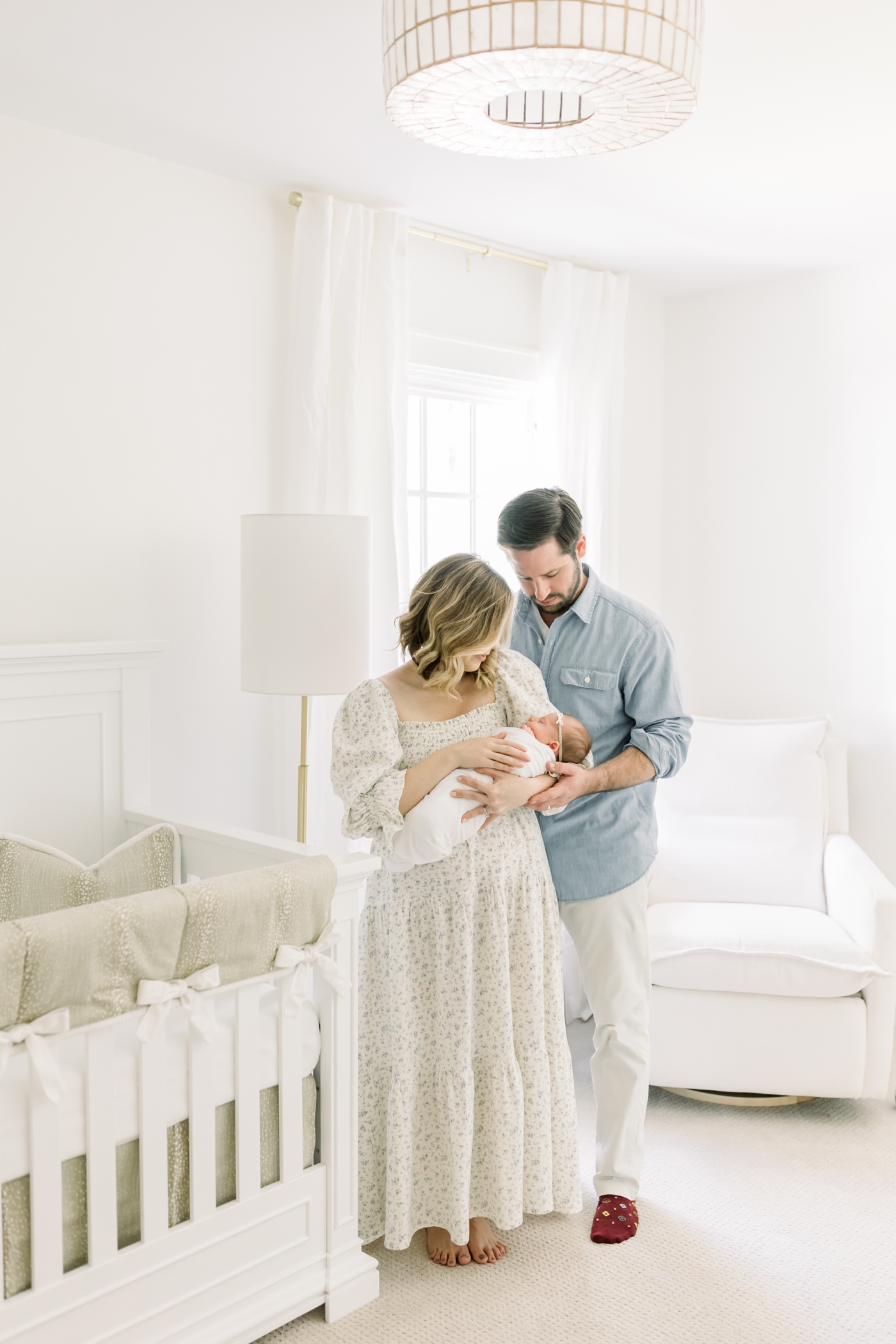 Mom and dad looking at their newborn baby in the nursery | Photo by Caitlyn Motycka Photography.