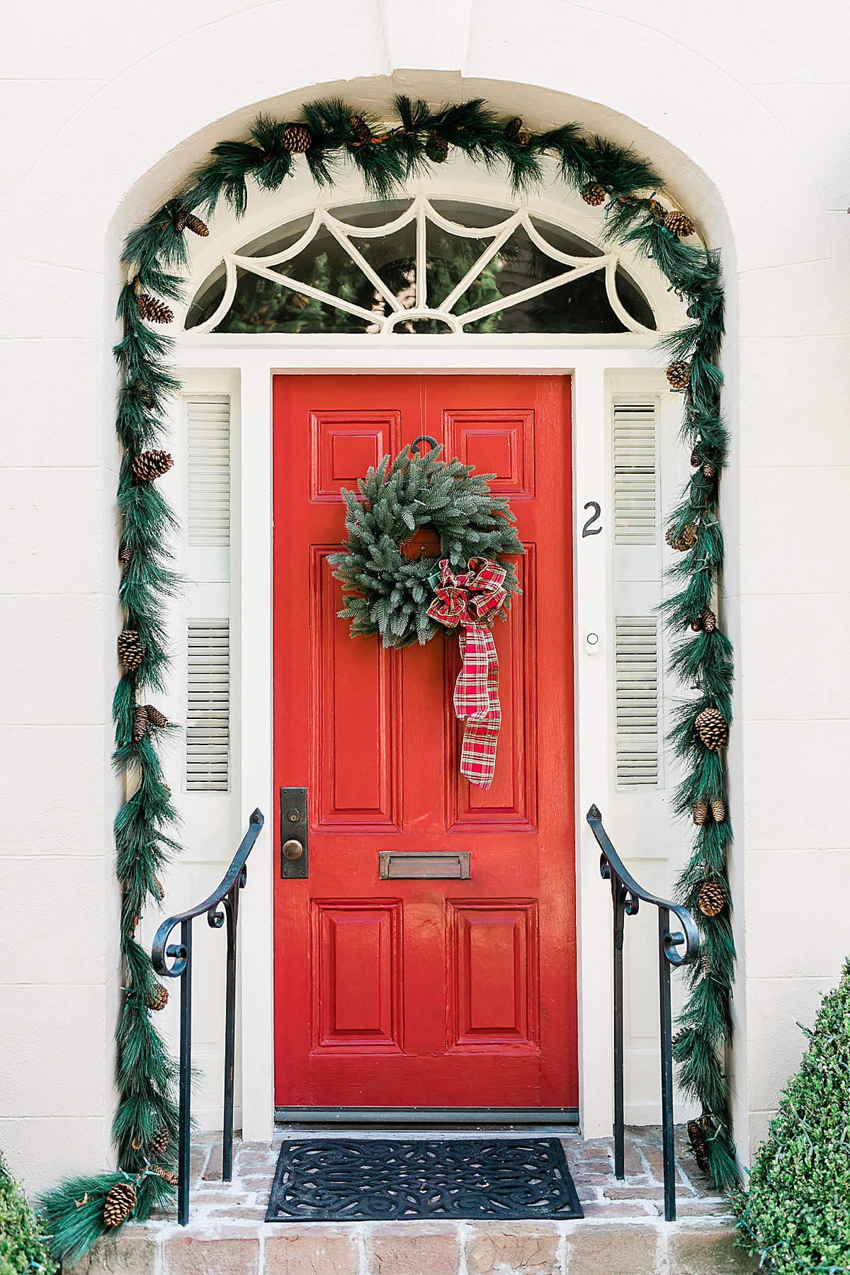 Festive red door with Christmas decorations in Charleston. Photo by Caitlyn Motycka Photography.