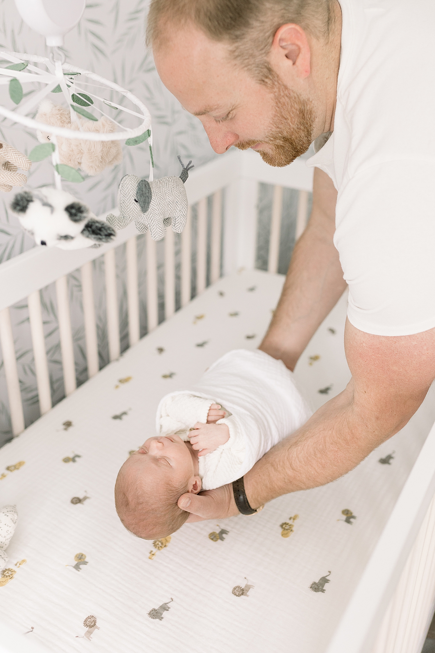 Dad putting his sleeping baby down in his crib | Photo by Caitlyn Motycka Photography