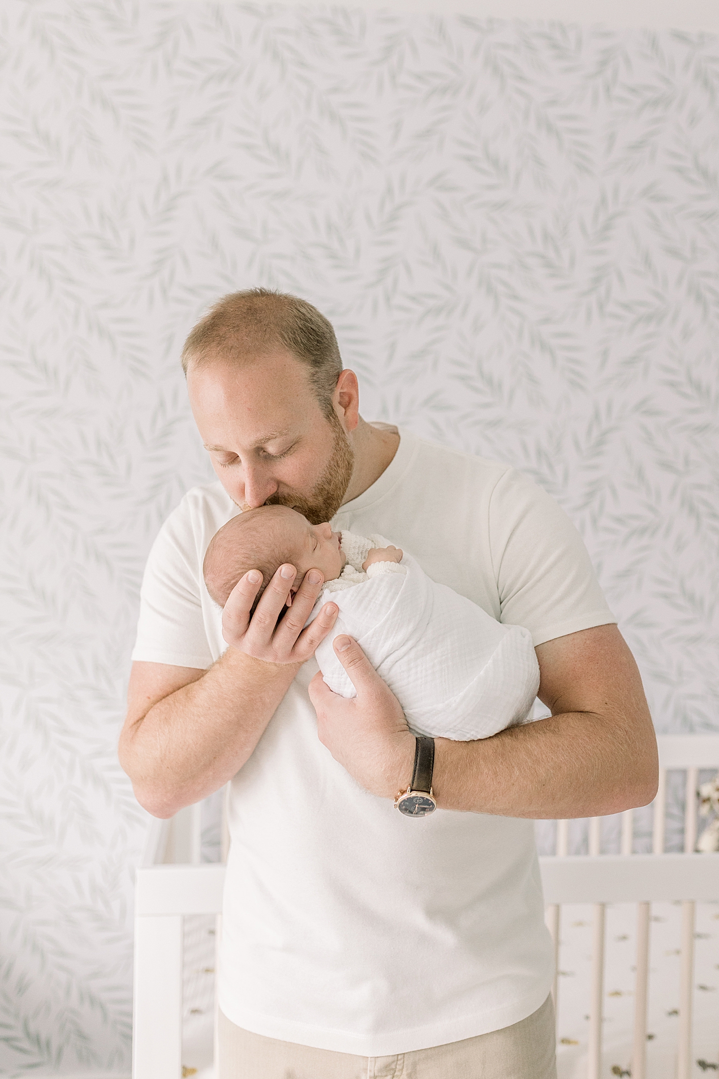 Dad kissing his newborn baby in their nursery | Baby Boy Newborn Photos CHS by Caitlyn Motycka Photography