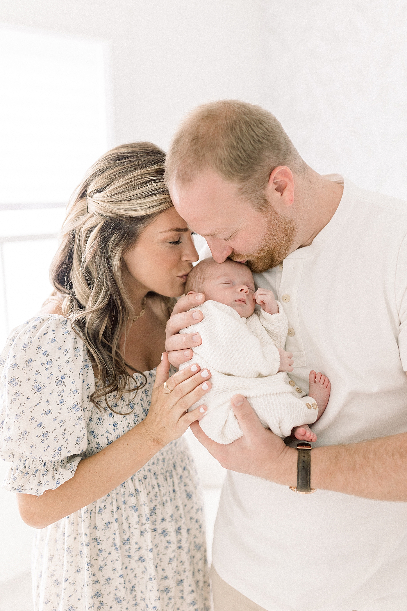 Mom and dad kissing their new baby during newborn photos | Photo by Caitlyn Motycka Photography