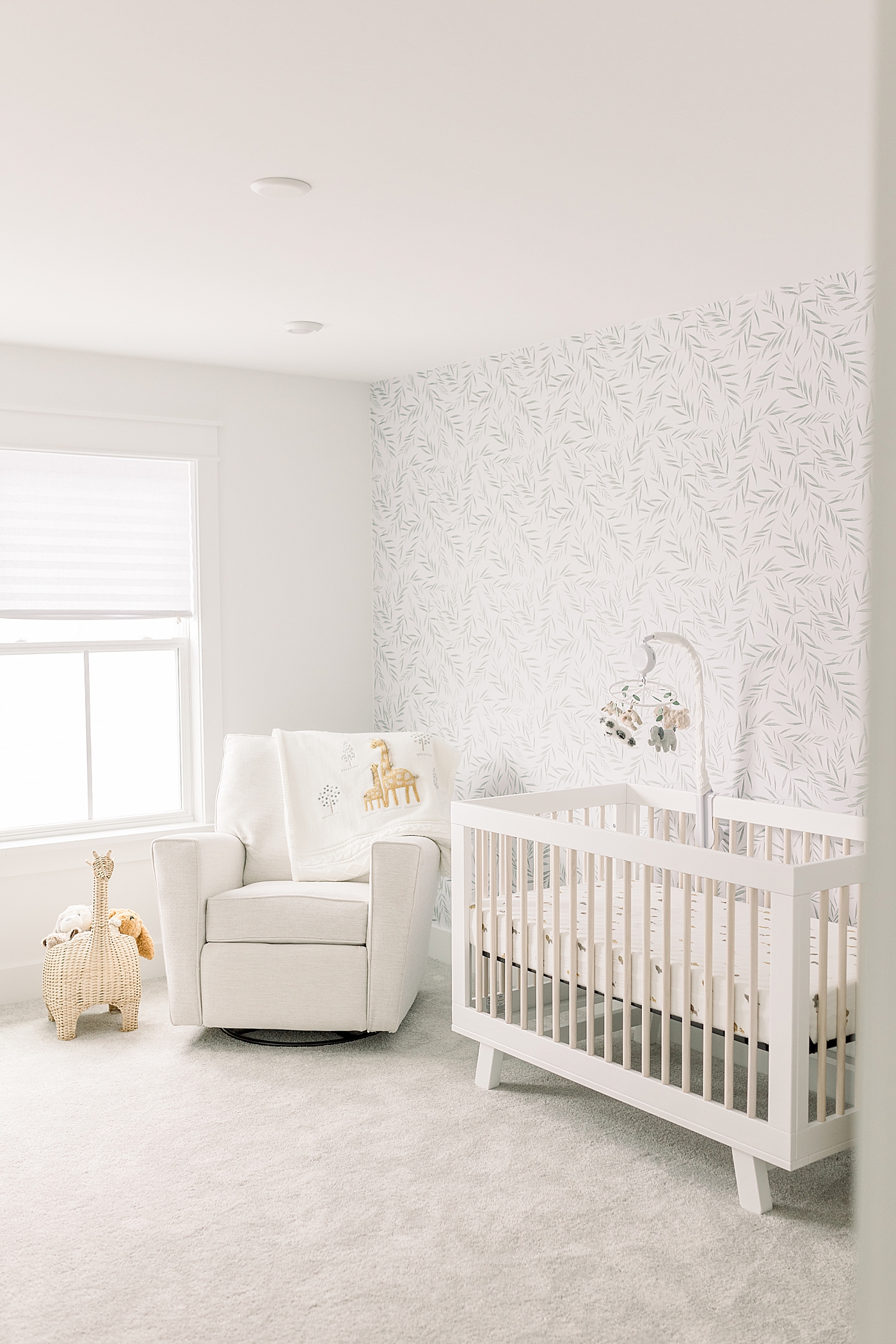 Baby boys nursery with crib glider and pretty wallpaper | Photo by Caitlyn Motycka Photography
