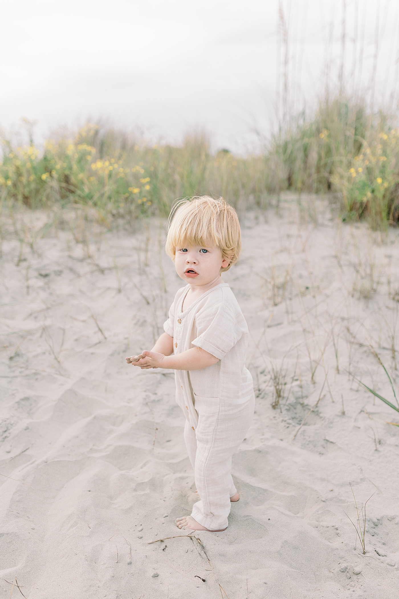 Little boy with blonde hair playing on the beach | Photo by Caitlyn Motycka Photography