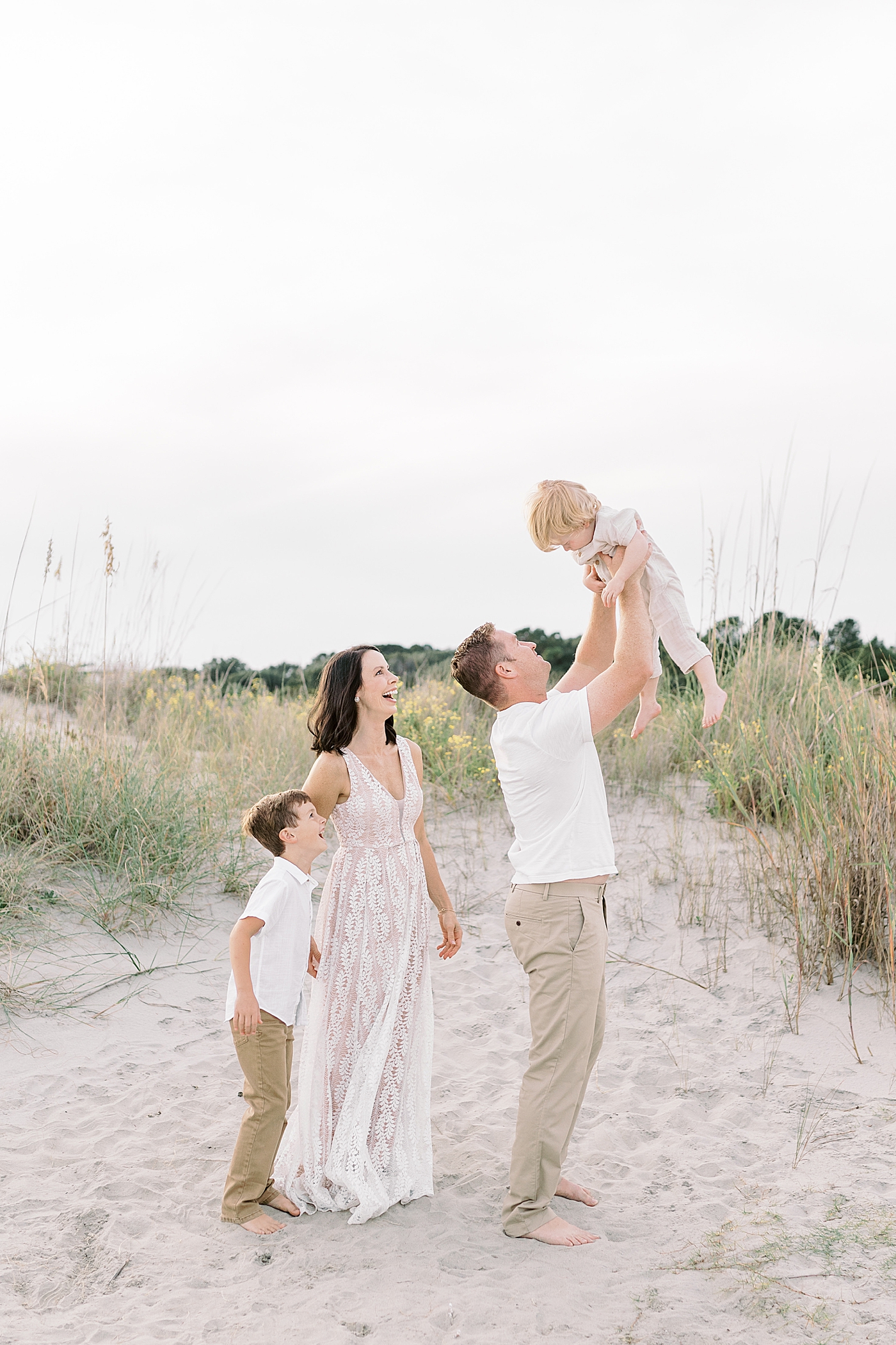Family of five playing near the dunes during fall family session at beach| Photo by Caitlyn Motycka Photography