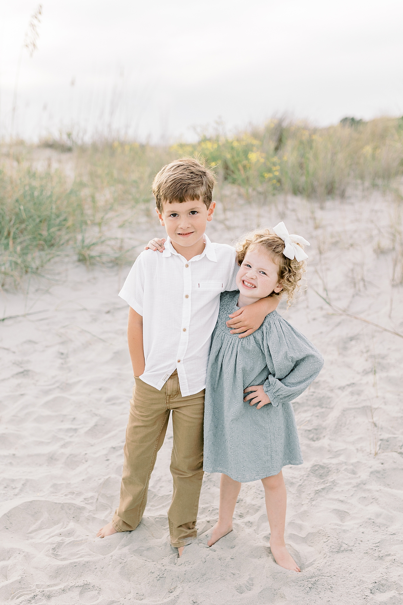 Brother and sister standing together on the beach | Photo by Caitlyn Motycka Photography