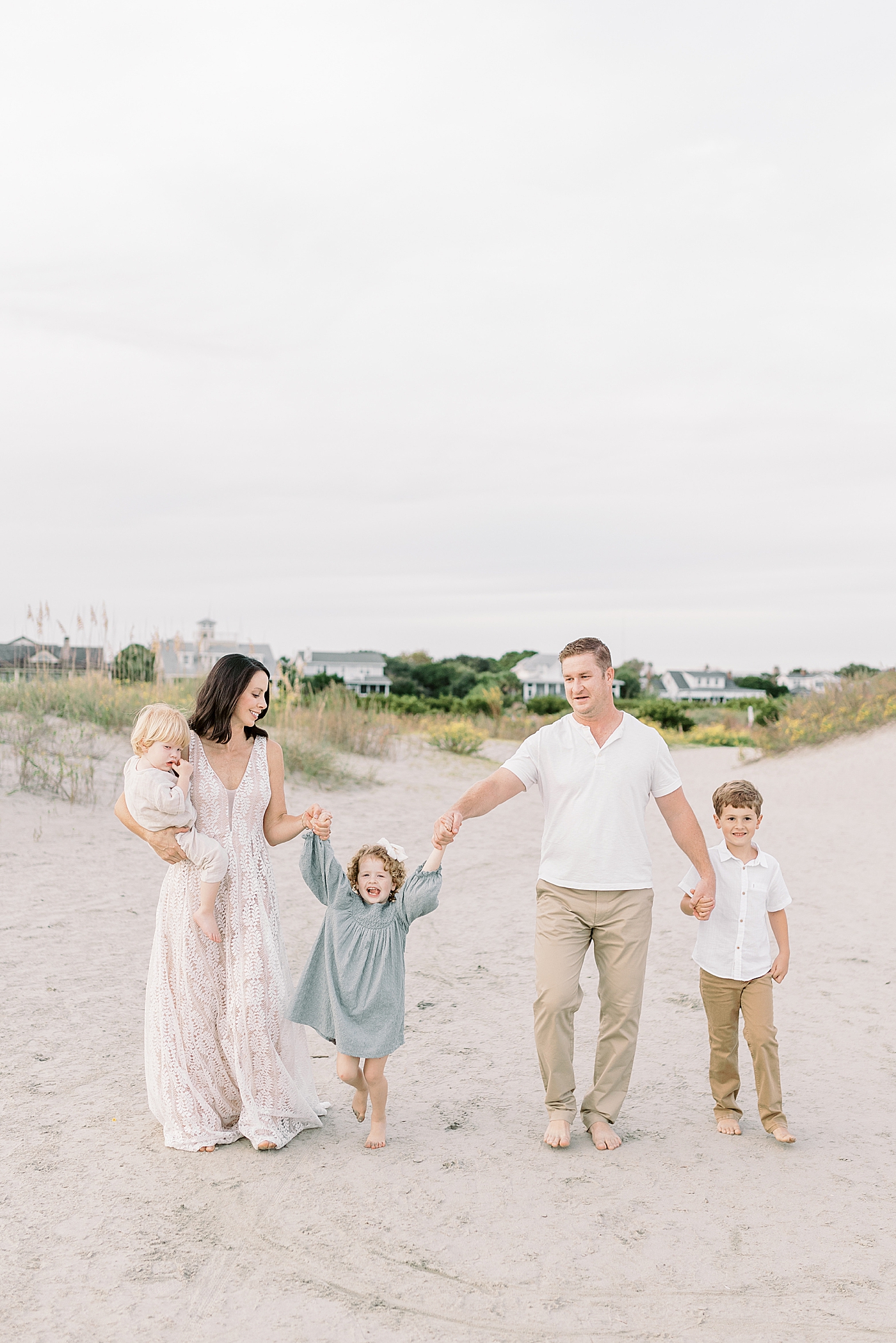 Family holding hands walking on the beach | Photo by Caitlyn Motycka Photography