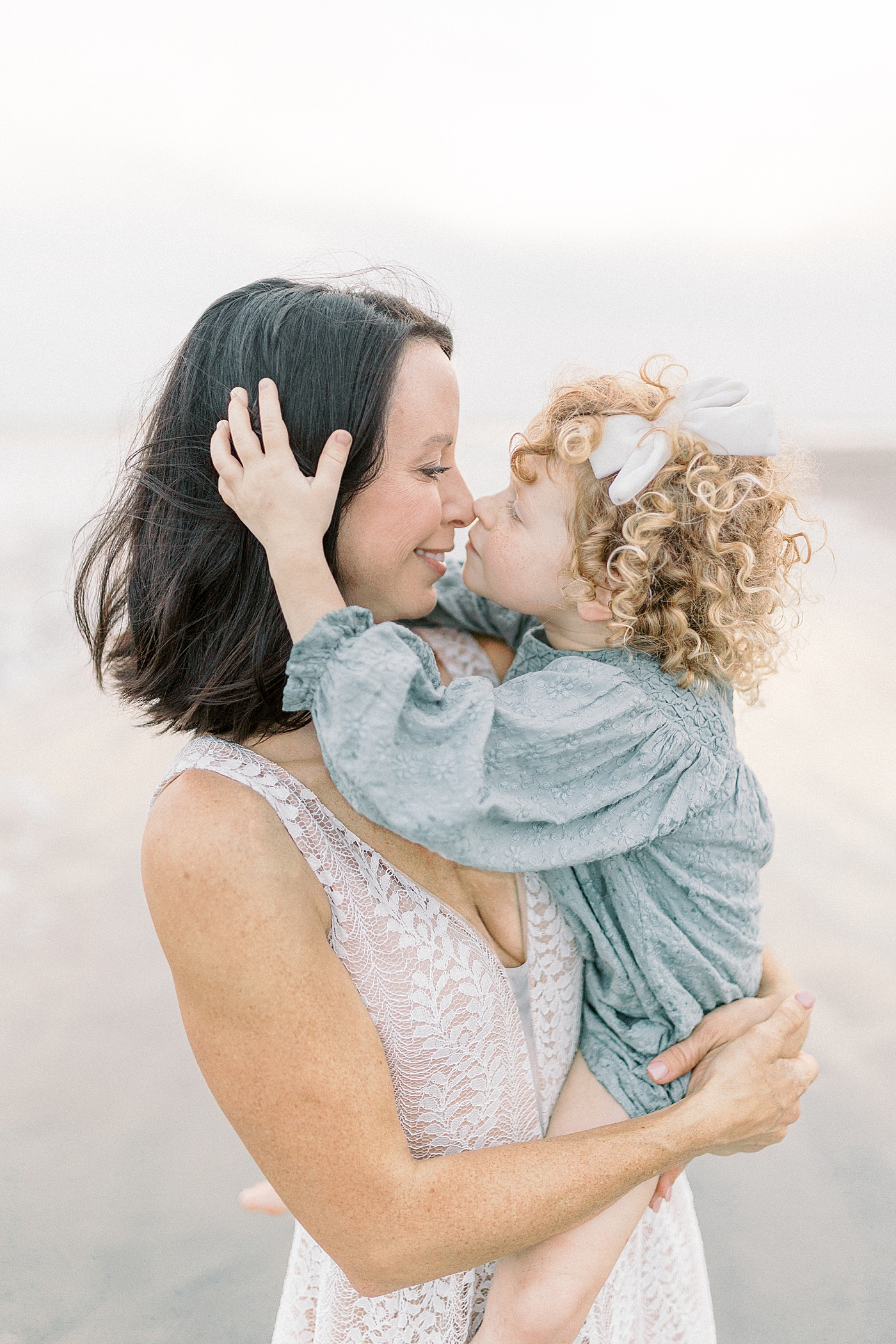 Mom and daughter snuggling during fall family session at beach | Photo by Caitlyn Motycka Photography