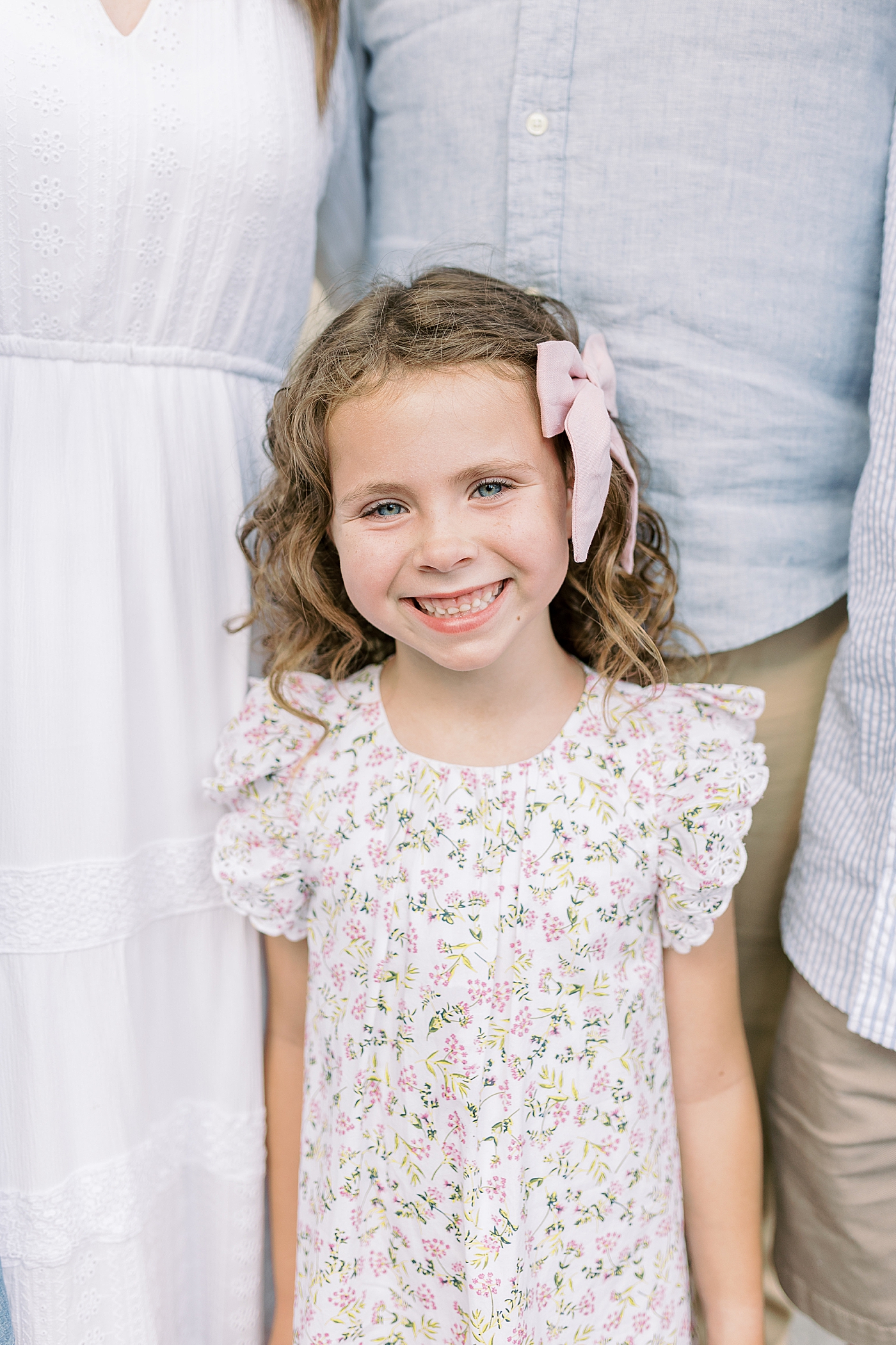 Little girl with a floral dress and pink bow smiling | Photo by Caitlyn Motycka Photography