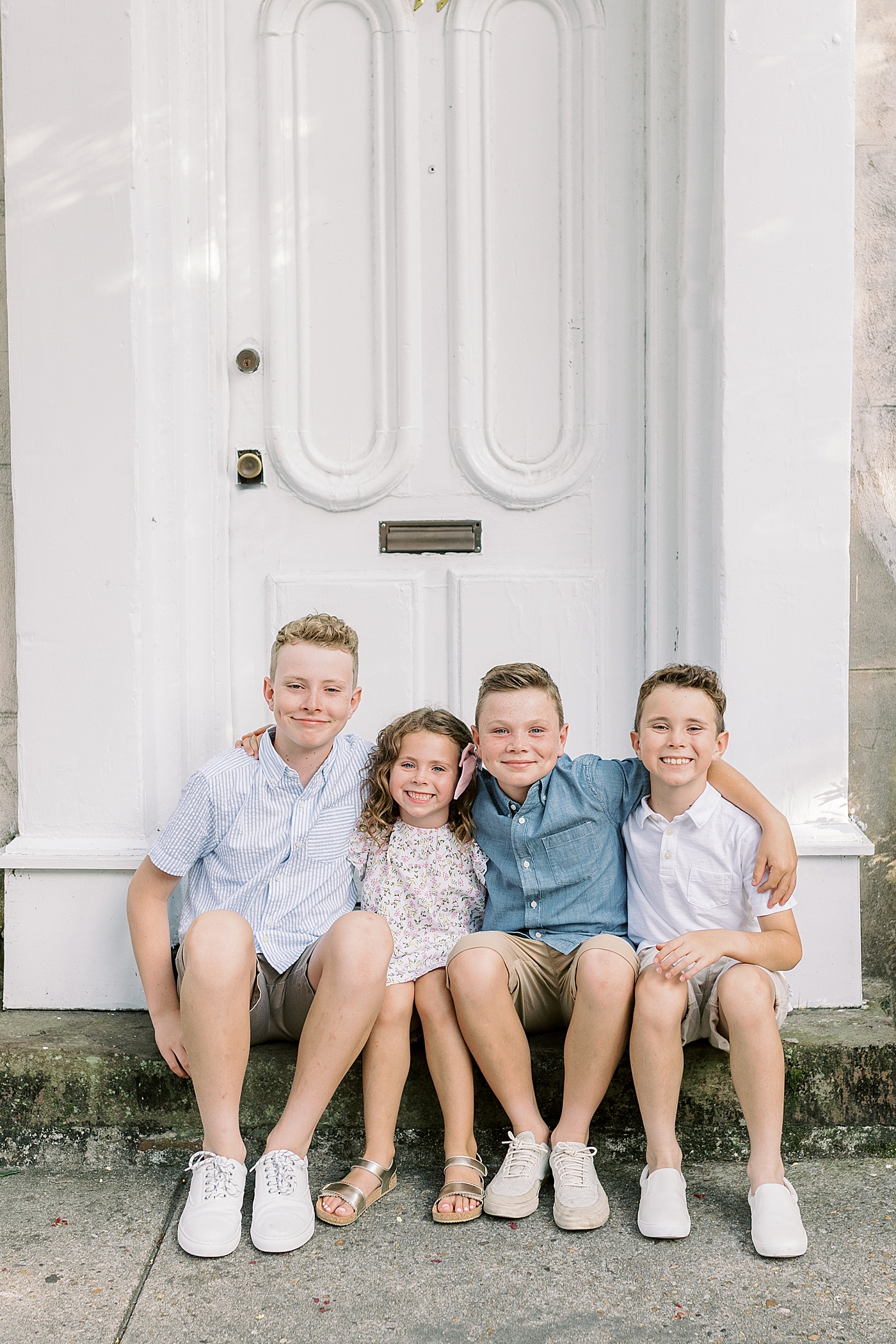 Siblings smiling sitting together on a stoop | Photo by Caitlyn Motycka Photography