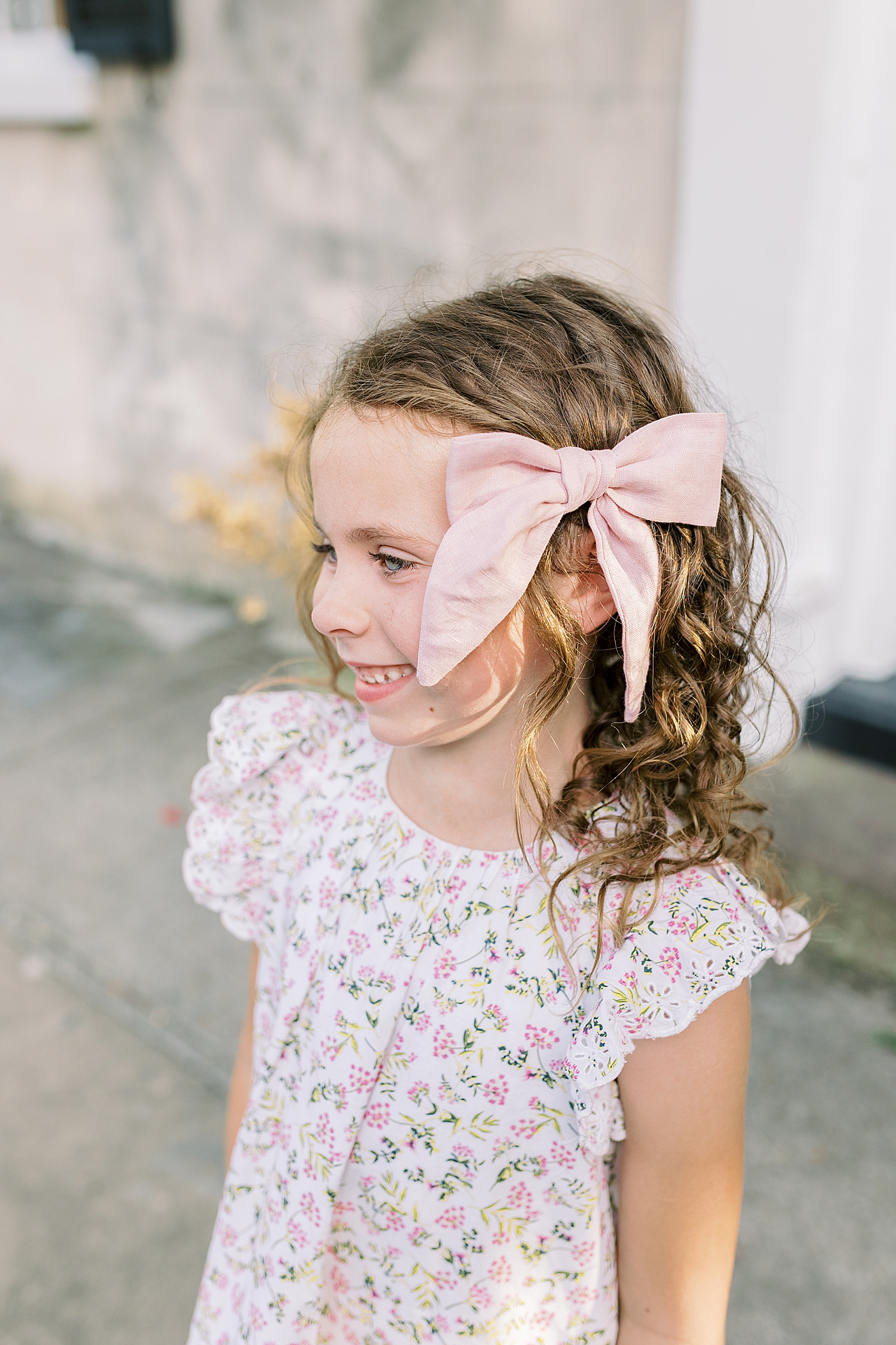 Little girl with a pink bow smiling | Photo by Caitlyn Motycka Photography